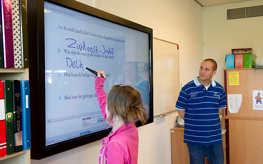 Een leerling schrijft iets op een digitaal schoolbord. Foto ANP