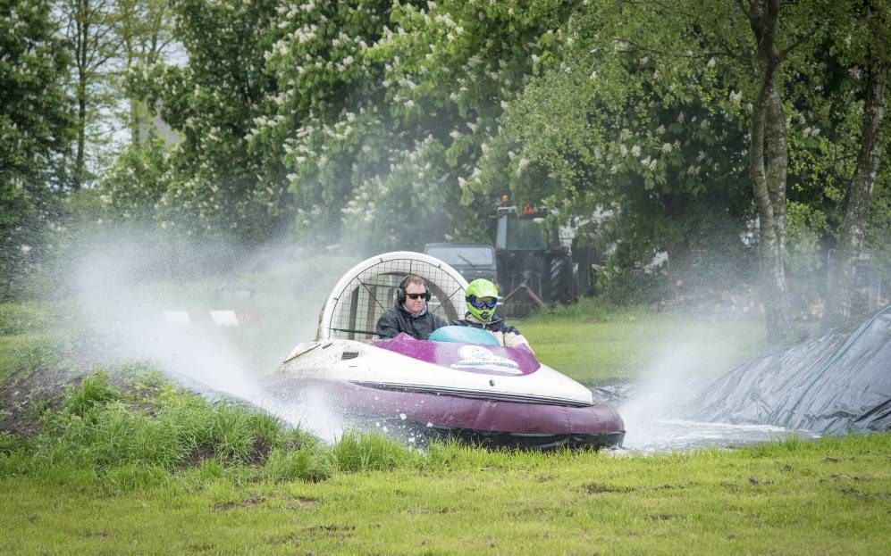 Ds. G. F. de Kimpe (r.) probeert een hovercraft uit. „Door het opspattende water ziet het er van een afstand in elk geval spectaculairder uit dan het in de hovercraft zelf is”, aldus zijn schoonzoon Dirk. beeld Niek Stam