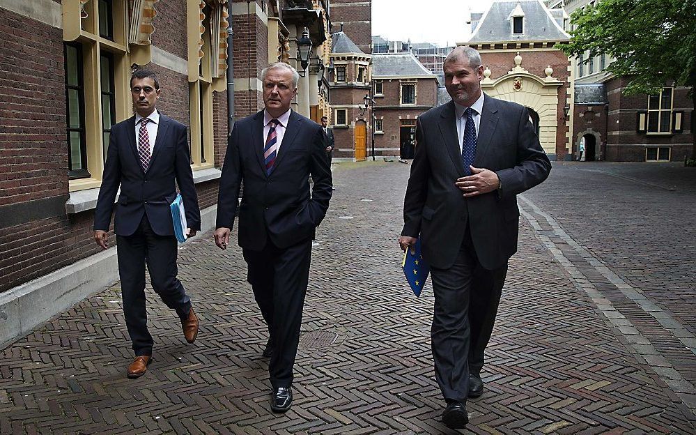 Rehn (midden) komt dinsdagmiddag aan op het Binnenhof. Foto ANP