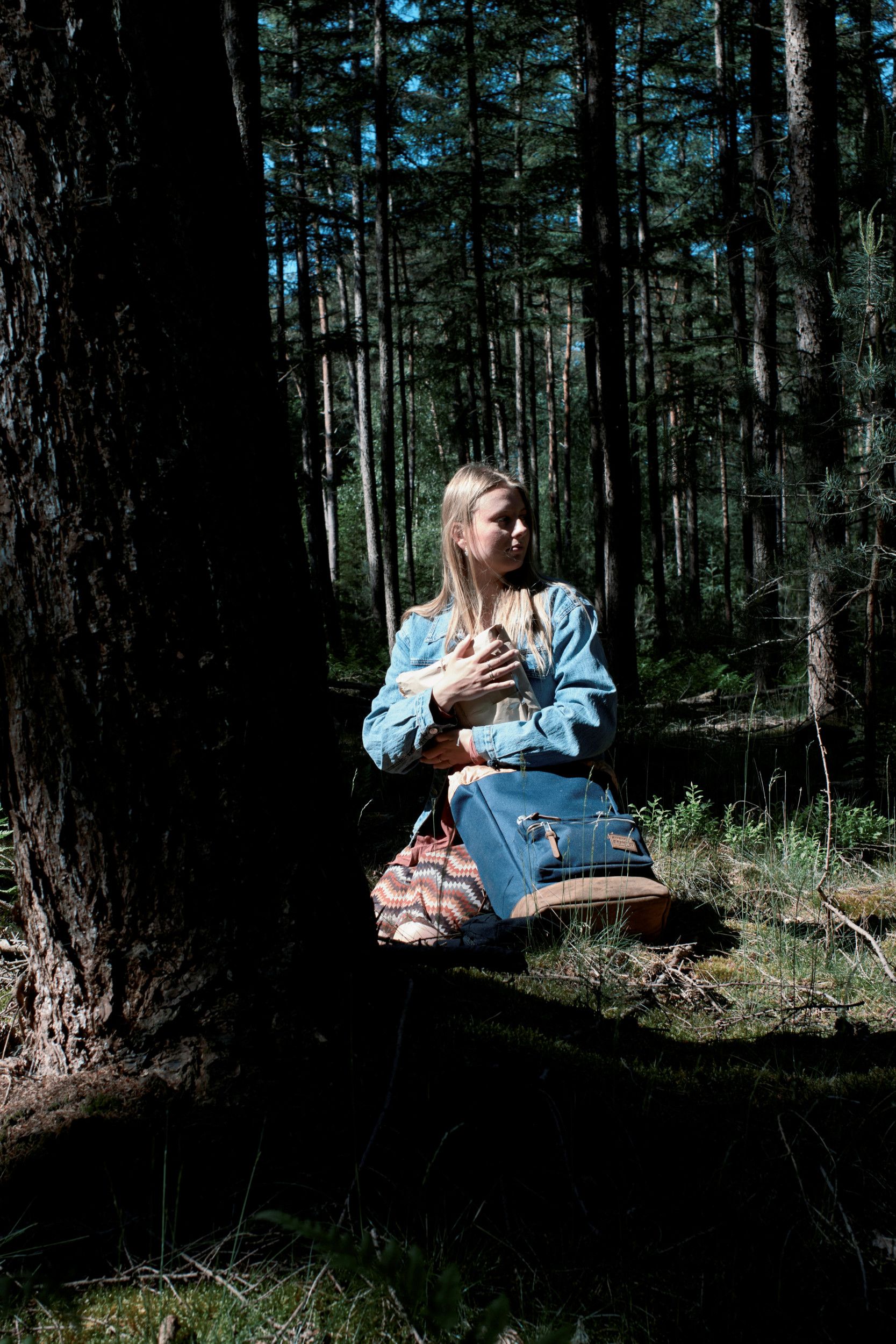 Meisje in het bos, een in bruin papier gewikkeld pakje in haar handen.