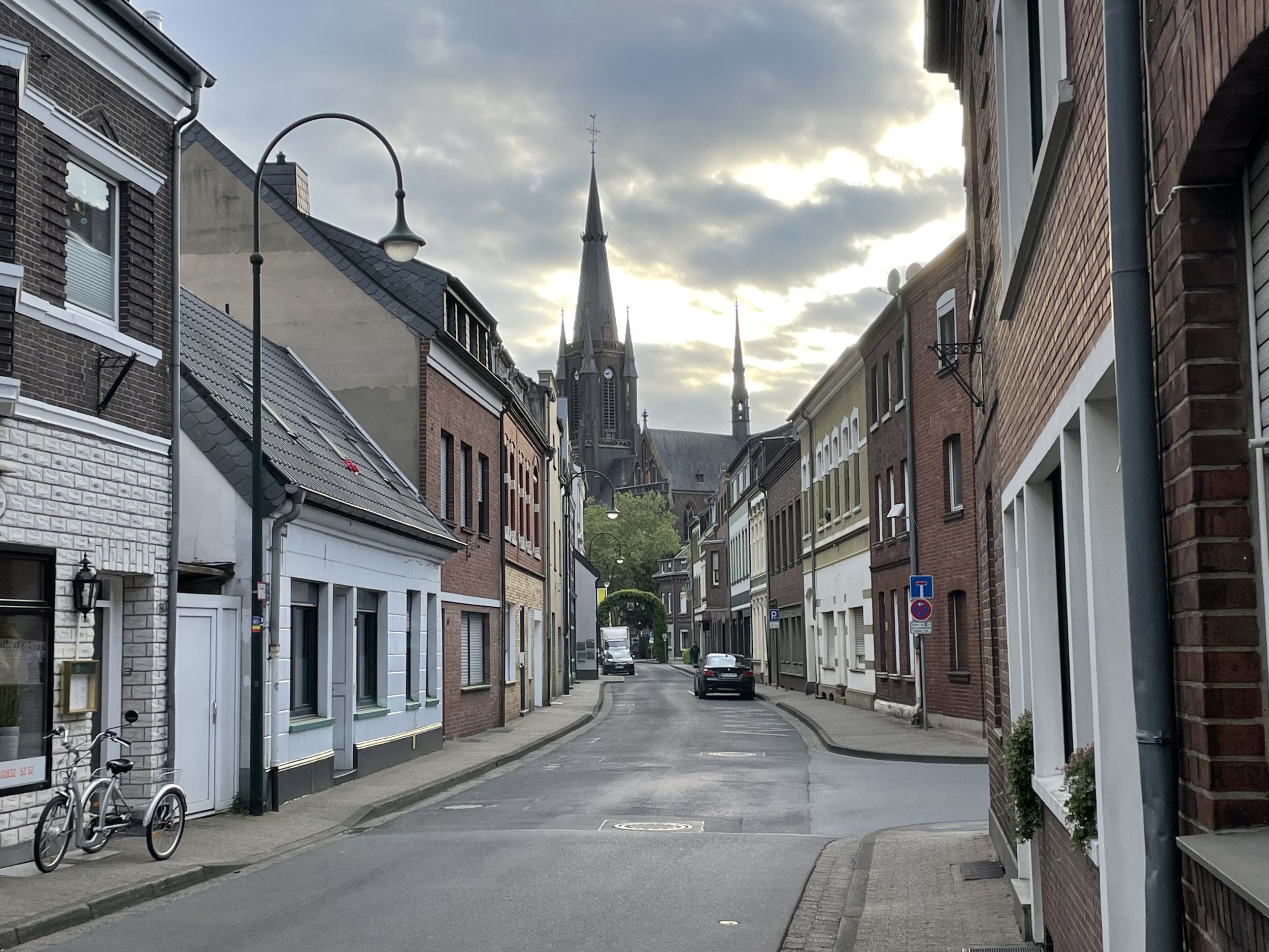 Straat met huizen aan weerskanten, uitlopend op een hoge kerktoren.