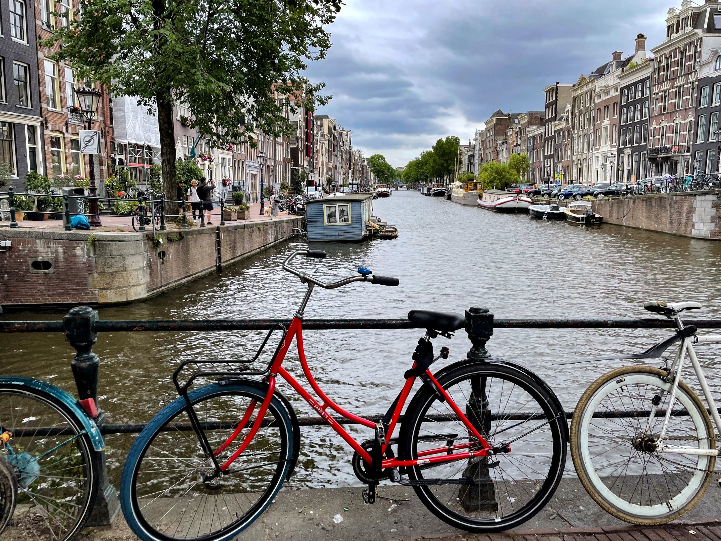 Gracht met aan weerszijden oude herenhuizen; op de voorgrond een rode fiets tegen de brugleuning.