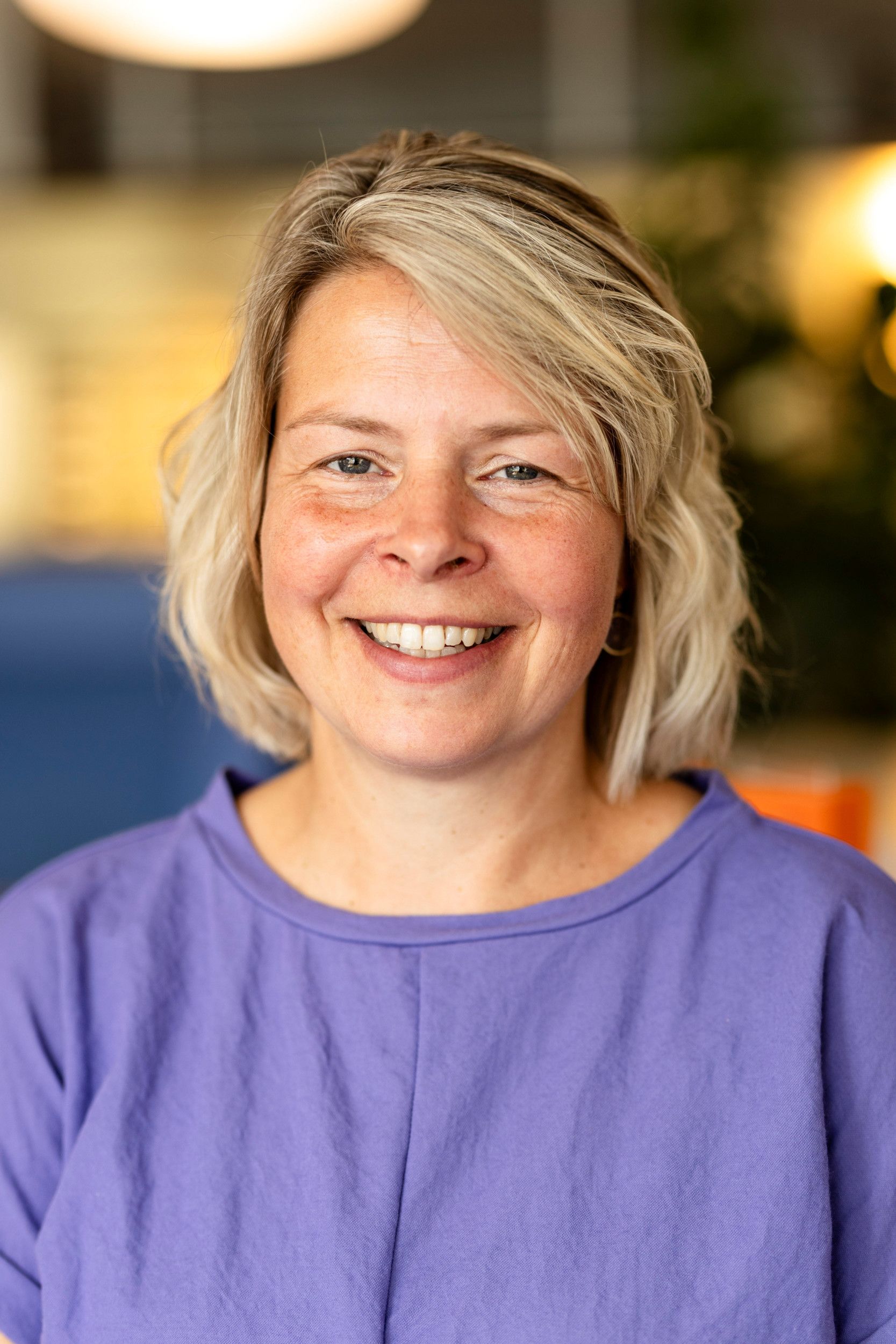 Portretfoto van een vrouw met een paarse jurk, blond haar en bruine ogen