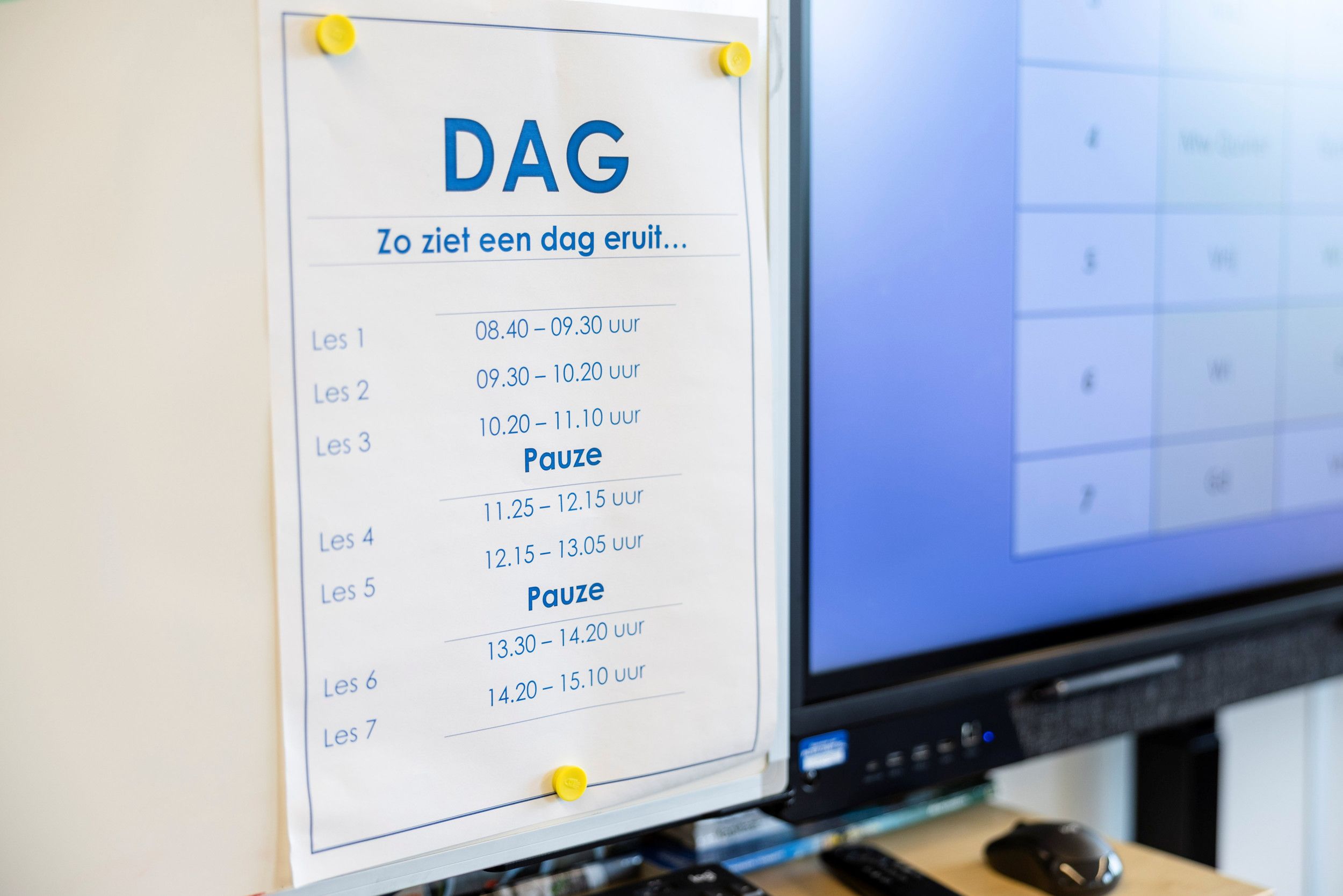 Een papier met een dagplanning hangt op het schoolbord. 