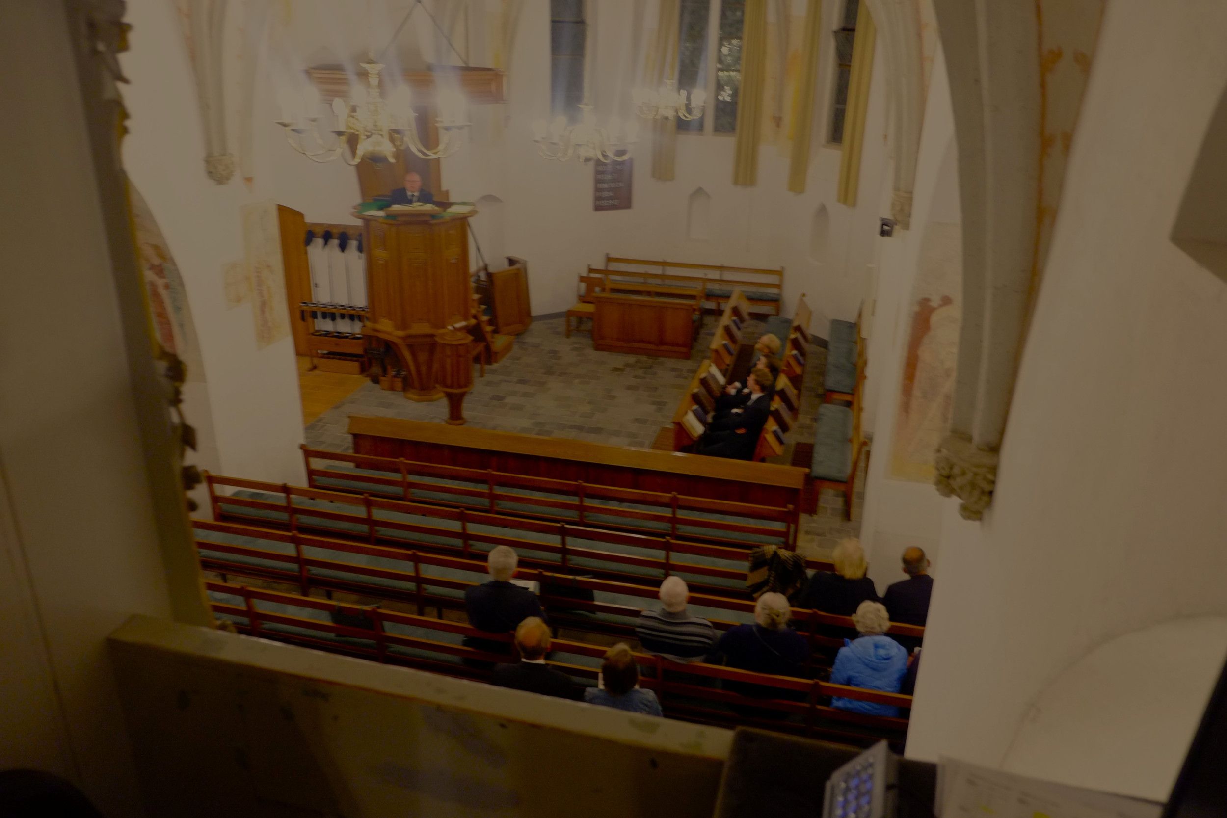 Kerkinterieur met in de banken een handjevol mensen.