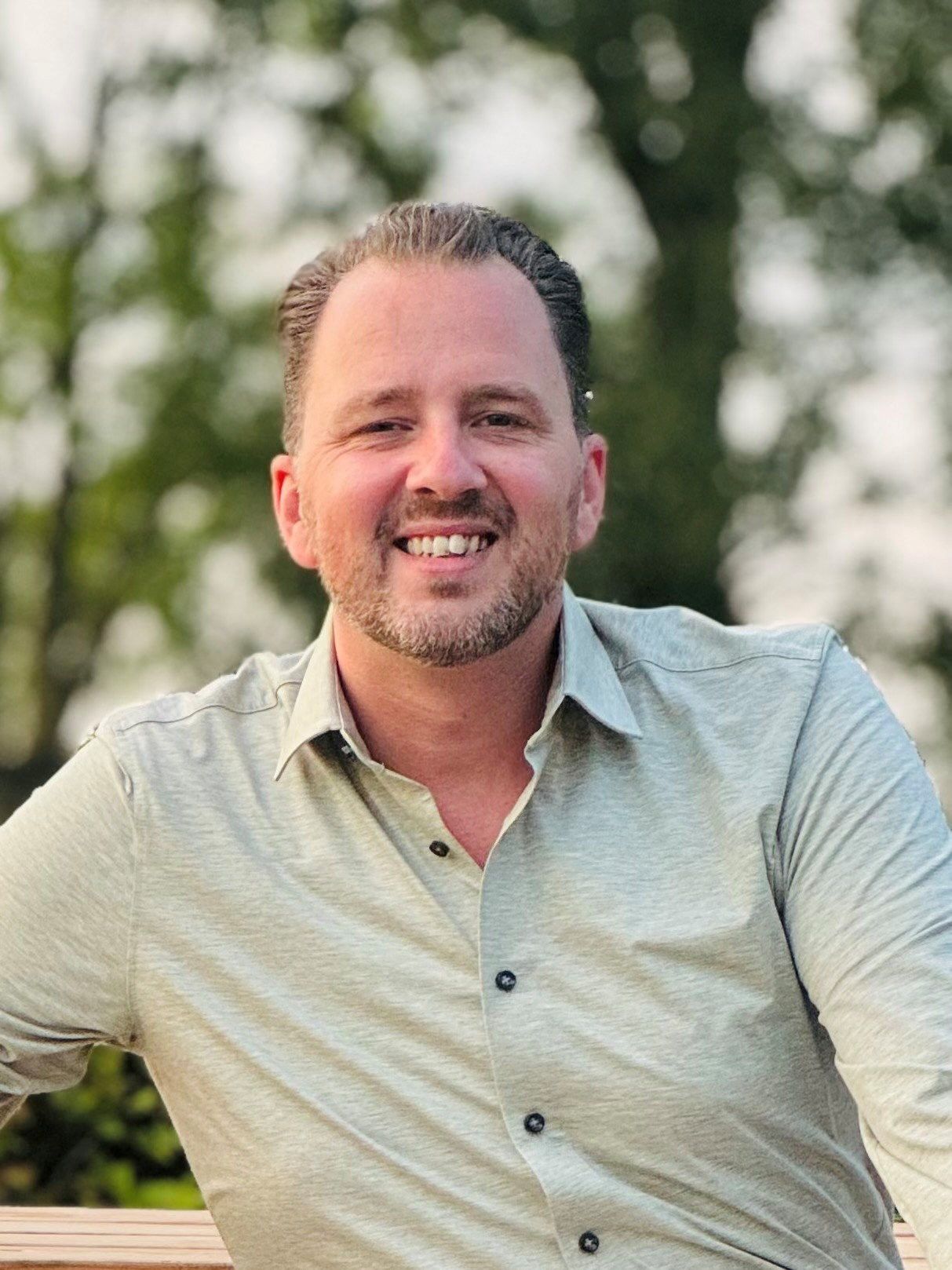 Foto van een man met baardje in groen overhemd.