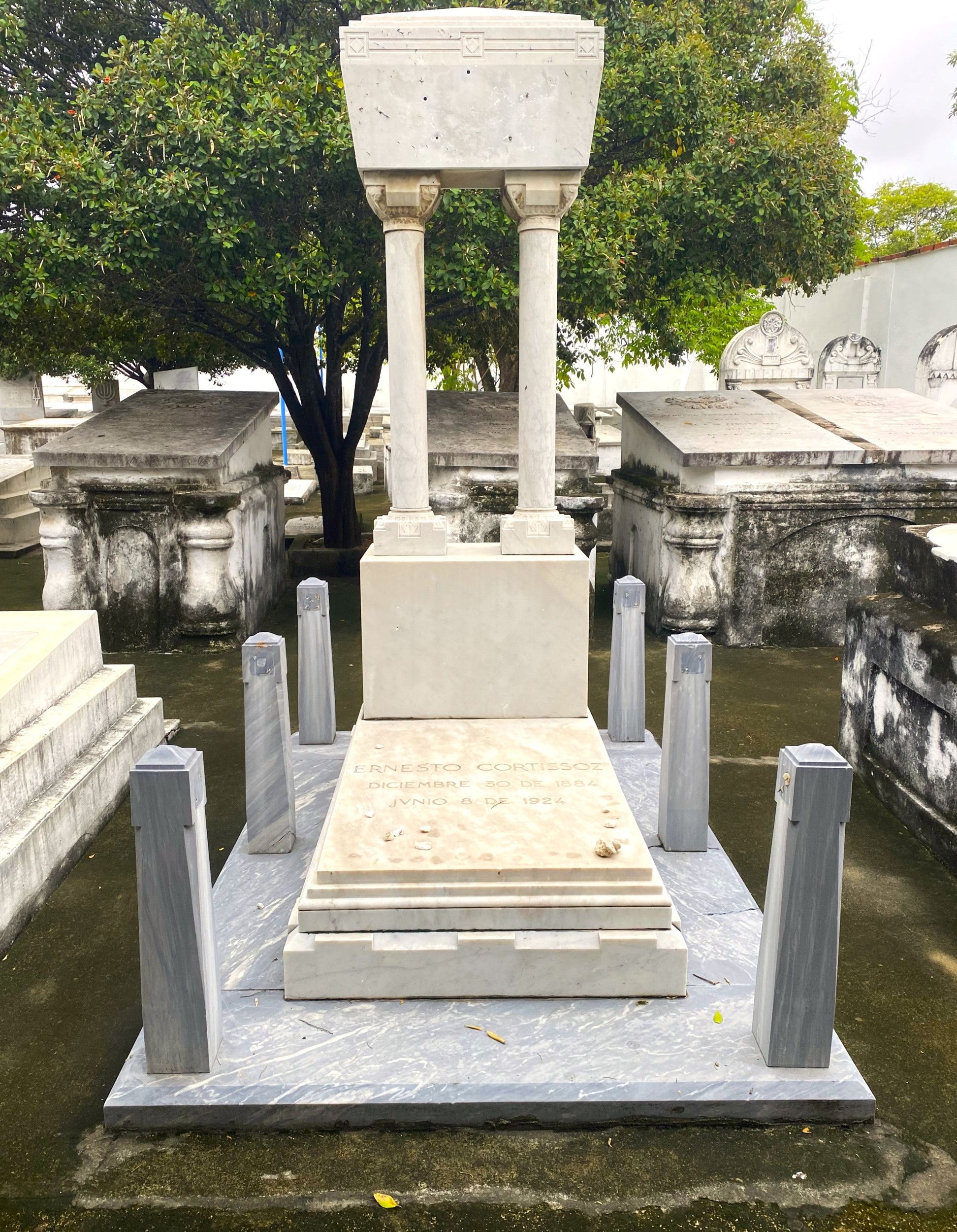 Grafmonument met paaltjes en zuilen. Het valt uit de toon ten opzichte van de klassieke graven eromheen.