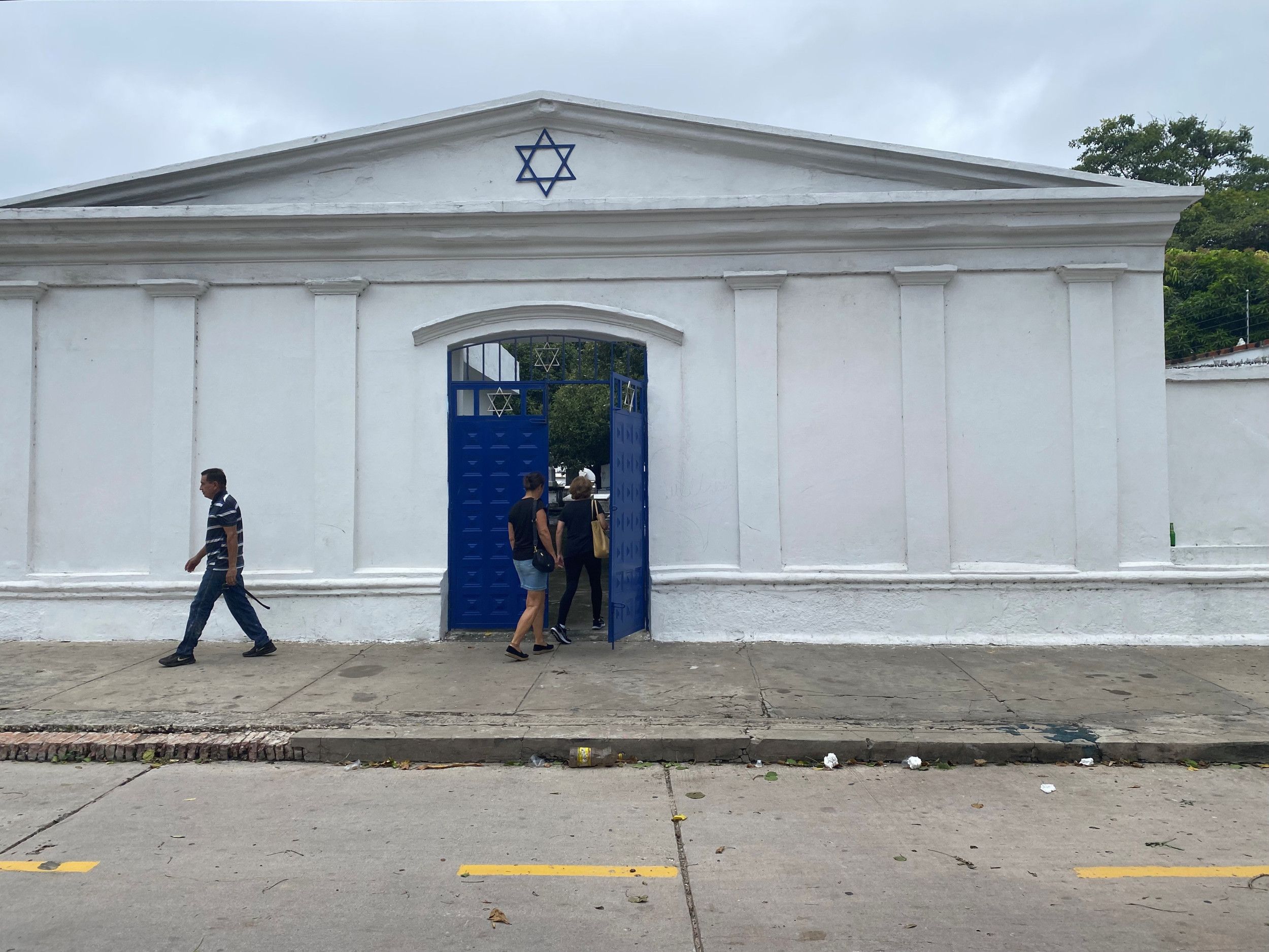 Mensen gaan door de poort die toegang verschaft tot de oude Joodse begraafplaats van Barranquilla. Boven de ingang een Davidsster.