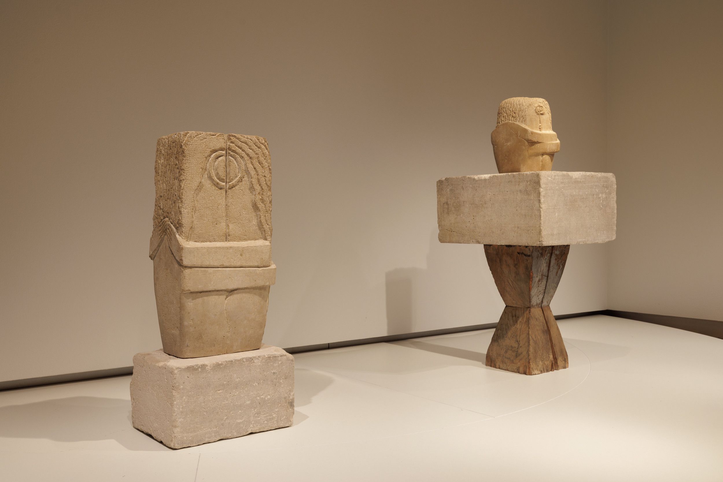 Twee beelden in een witte zaal in een museum. Beide laten een paar zien dat elkaar omhelst en kust.