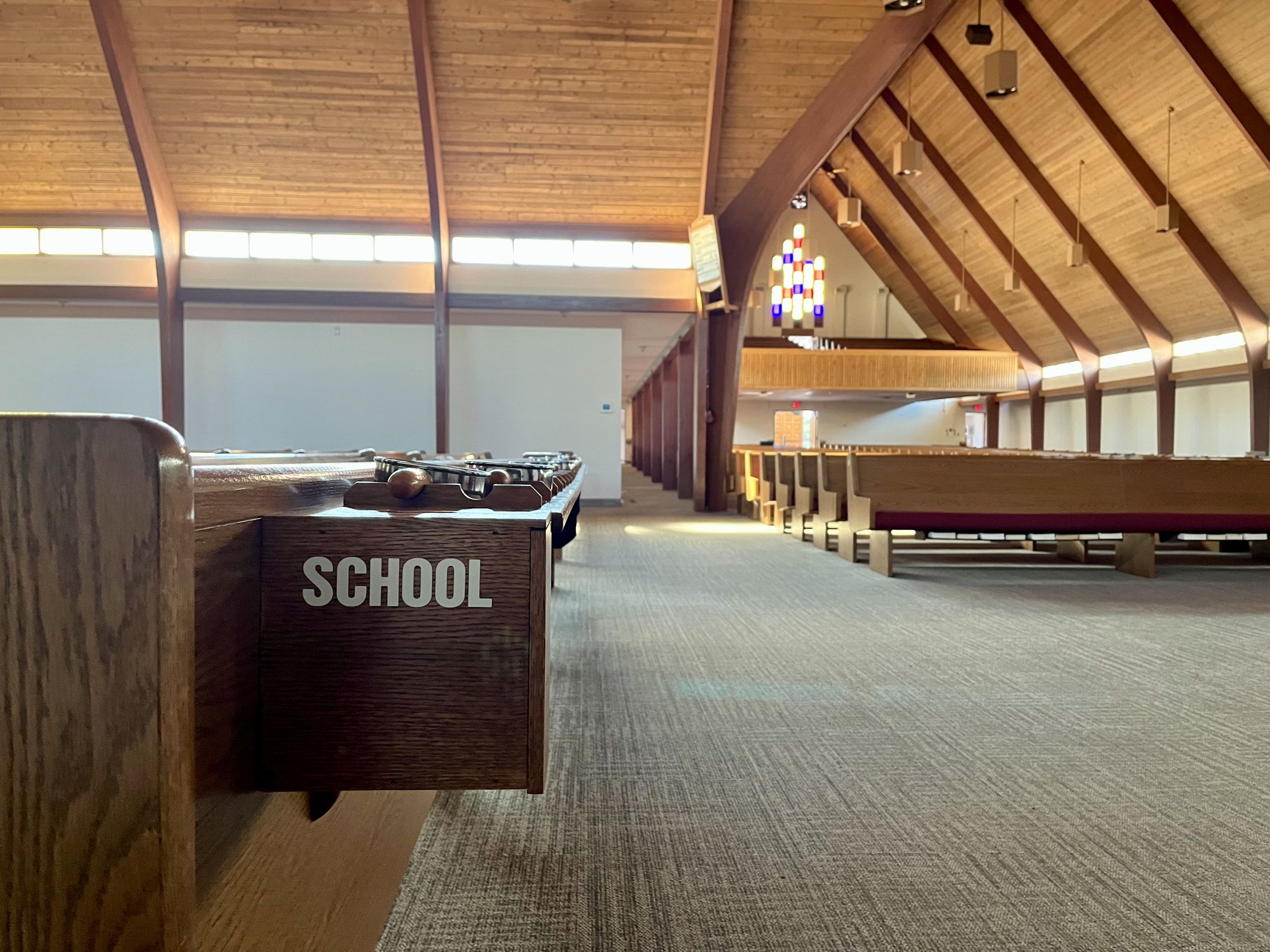 Interieur van een Canadees jarenzestig kerkgebouw met op de voorgrond collectezakken.