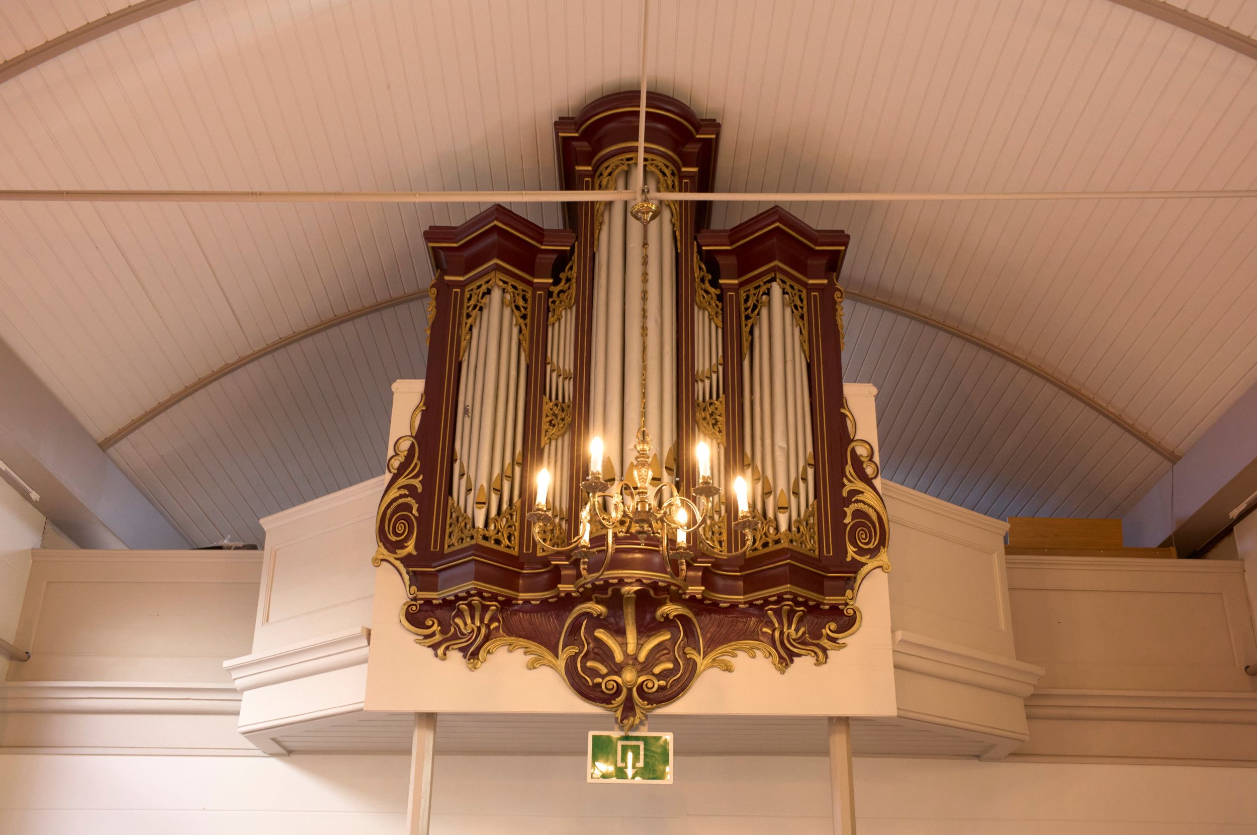 Een klein orgel, op een galerij.