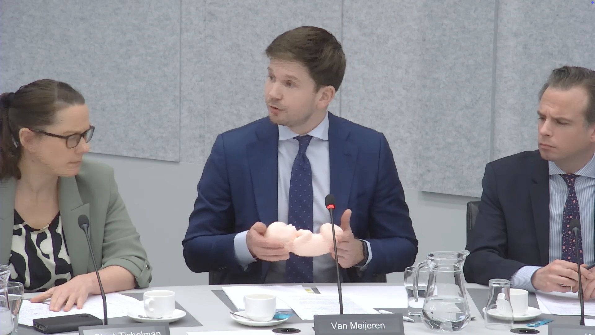 Man in pak heeft een modelfoetus in zijn hand.