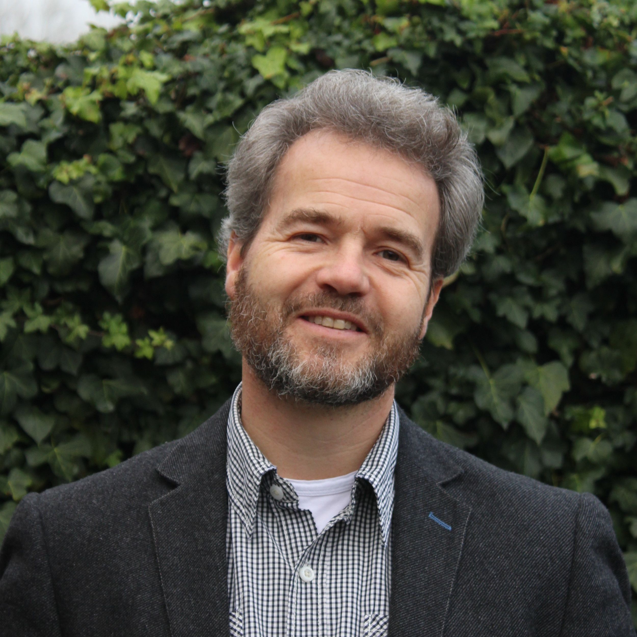 Dominee Visser, een man met zwart-grijs haar en baard.