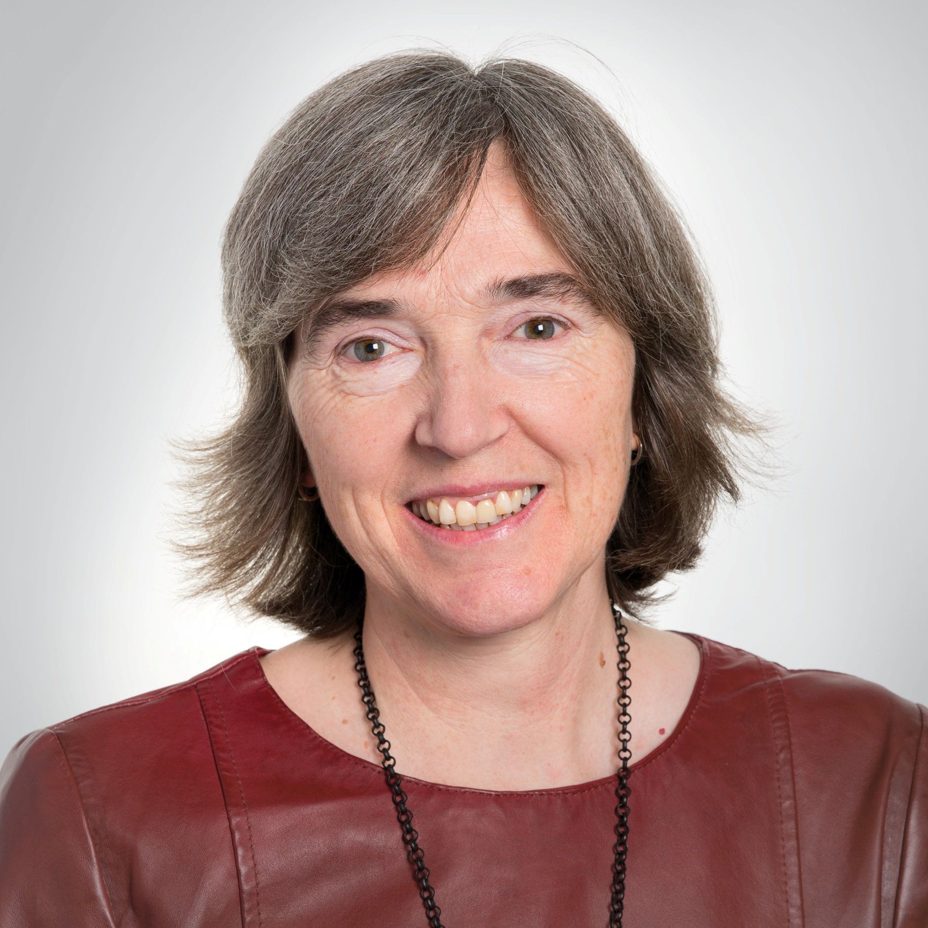 Vrouw met grijs halflang haar en bordeauxrood tuniek