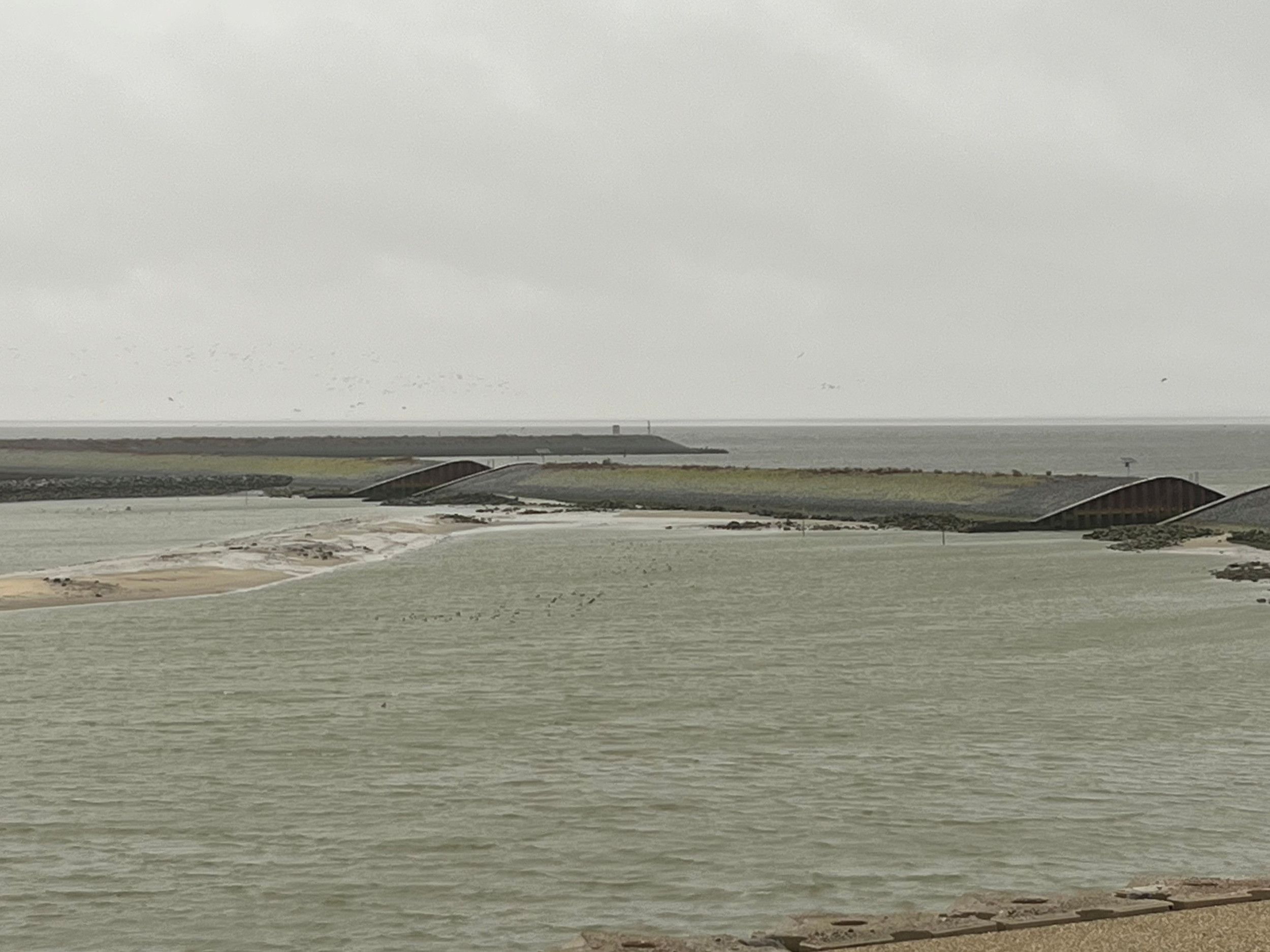 Dam van stenen in de zee met twee openingen erin.