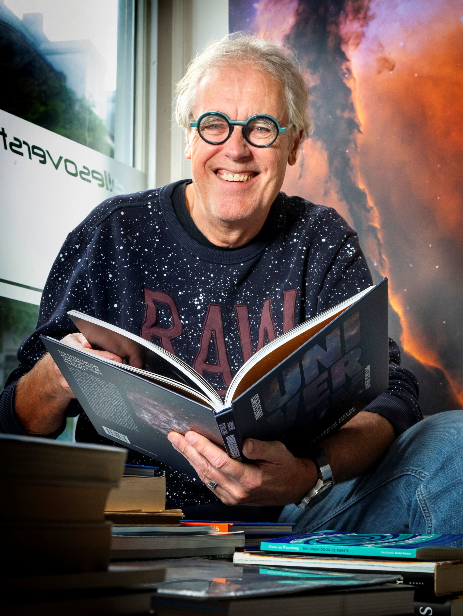 Man achter tafel met boeken, bladerend in een boek.