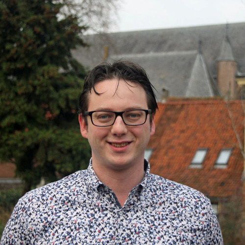 Witte man met zwarte bril en bloemetjesblouse.