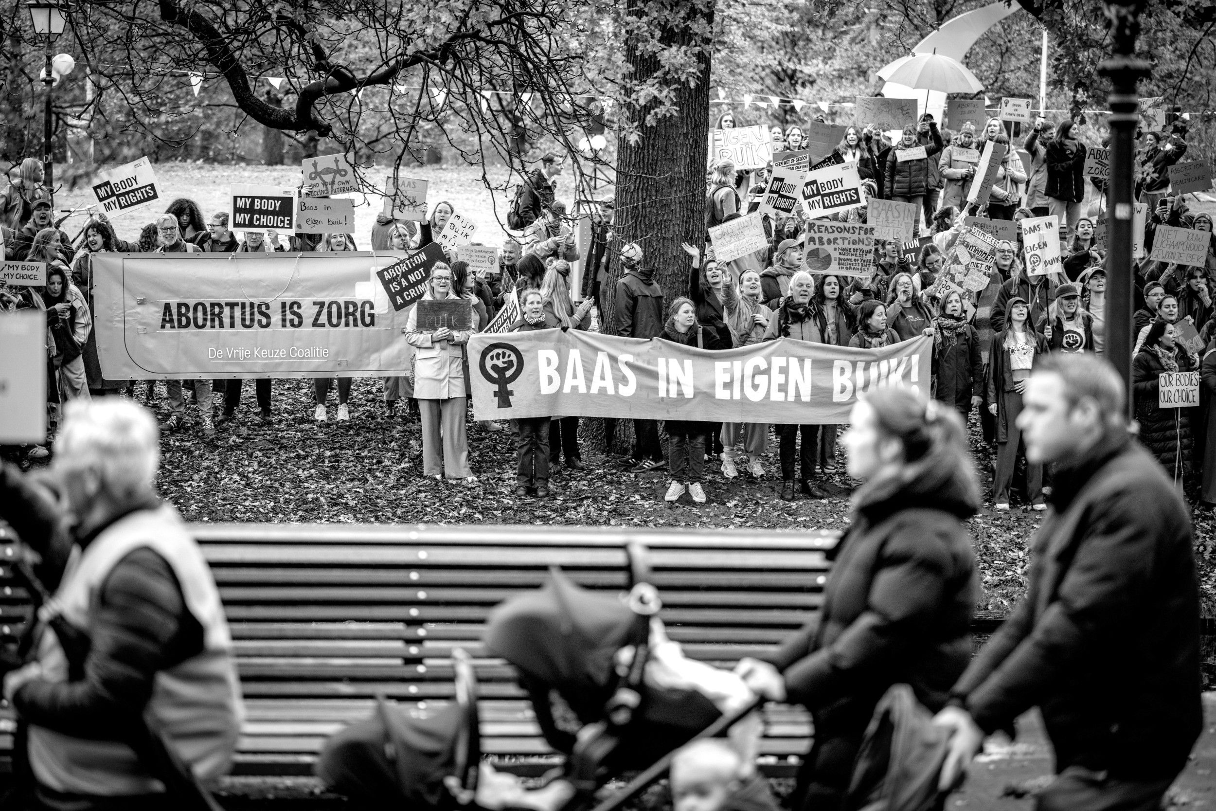 Ouders met kinderwagens nemen deel aan de Mars voor het leven. Op de achtergrond protesteren Dolle Mina’s met de leus ”Baas in eigen buik”.