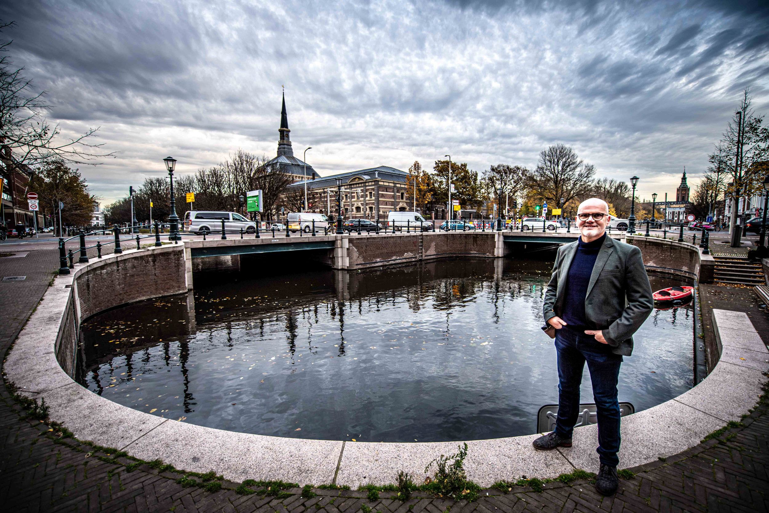 Donker geklede man naast een meer in een stad.