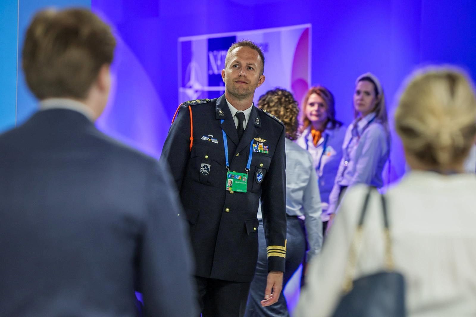 Man in uniform  tegen een achtergrond van NAVO-blauw.