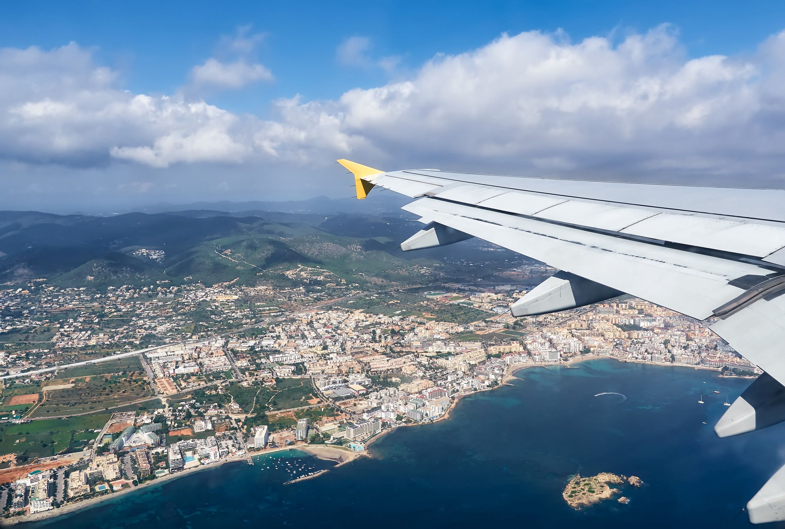 Prachtig uitzicht vanuit een vliegtuig op het eiland en de lucht van Ibiza, Balearen, Spanje. Witte vliegtuigvleugel in vlucht.