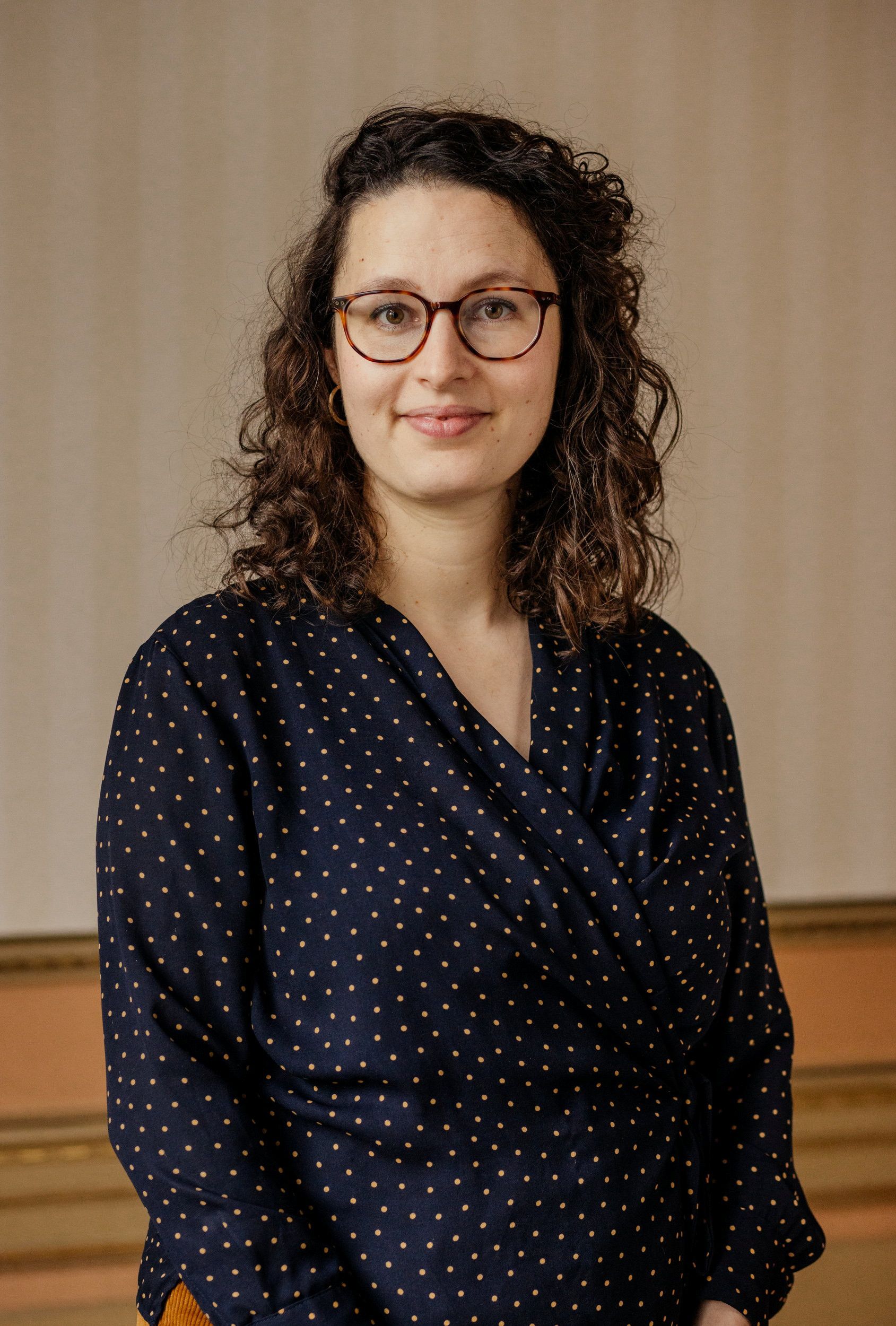 Vrouw in donkere jurk en met bruine bril.