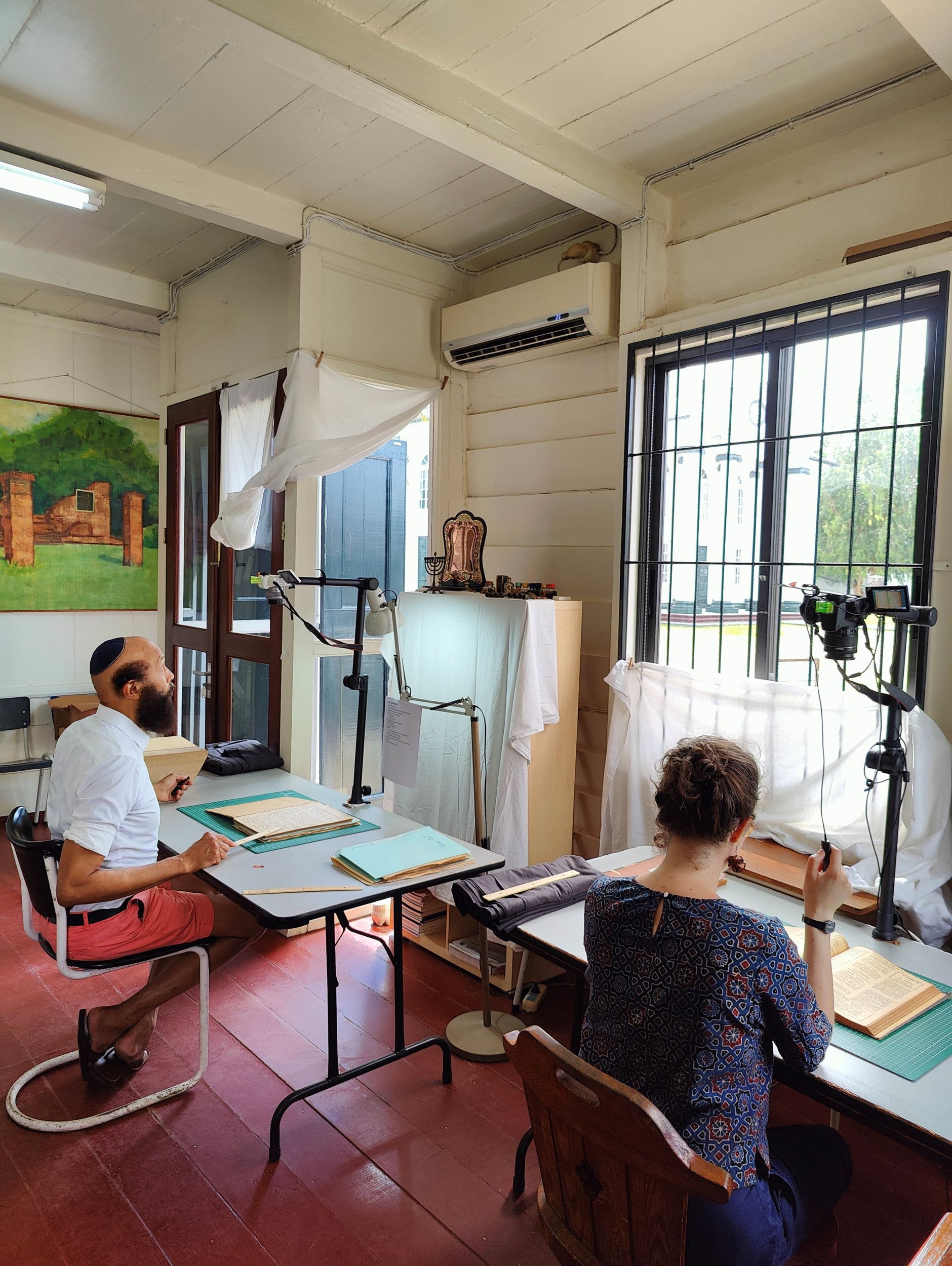 Vrouw drukt op knop scanapparaat, naast man met keppeltje en rode korte broek.