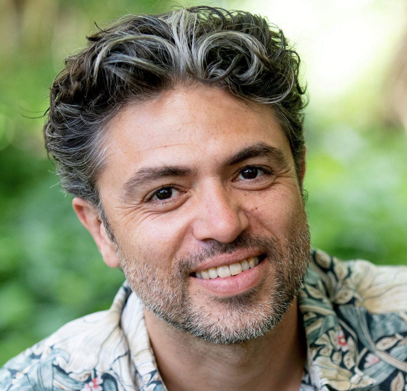 Man, veertiger, met stoppelbaard en gebloemde blouse aan.