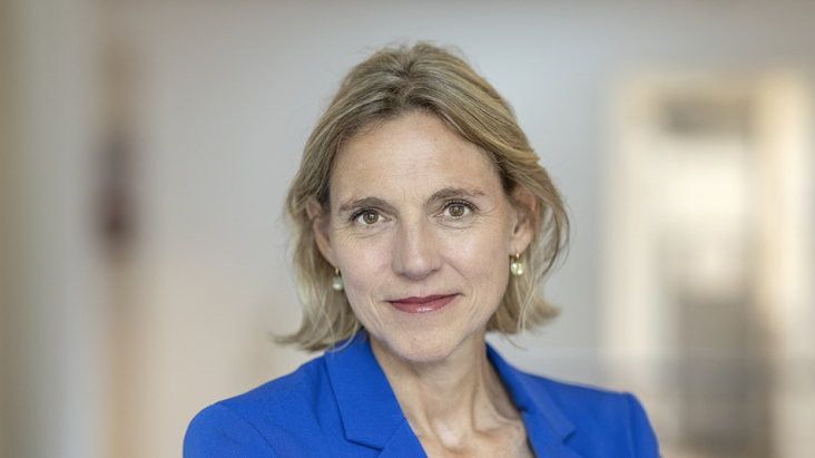 Blonde vrouw met blauw jasje.