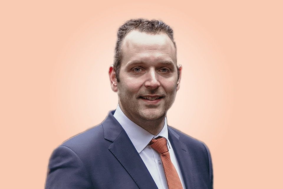 Man in blauw kostuum met oranje stropdas.