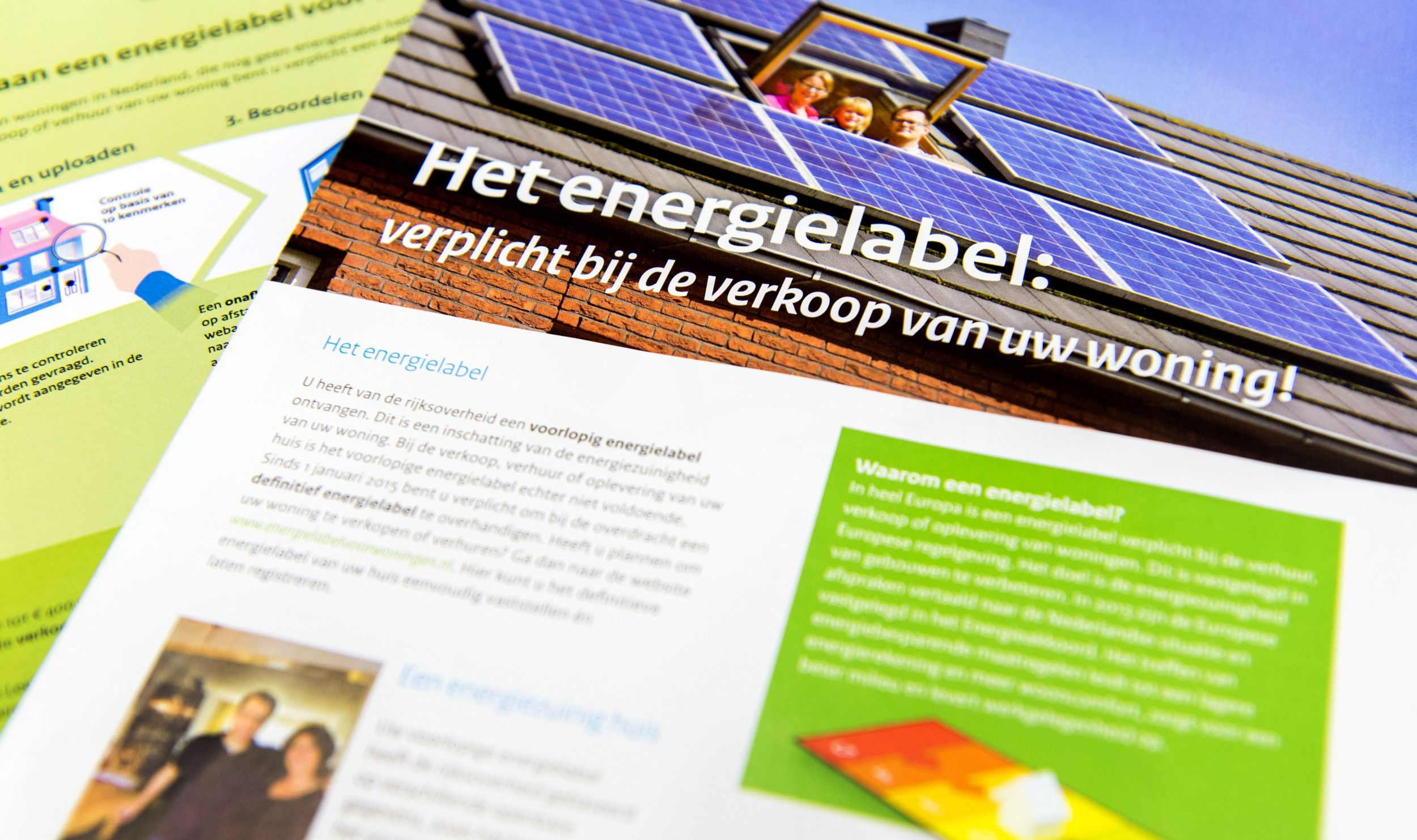 Een folder met uitleg over het energielabel voor woonhuizen. Met o.a. een foto van een dak bedekt met zonnepanelen waartussen een dakraam openstaat waaruit drie mensen naar de camera kijken.  