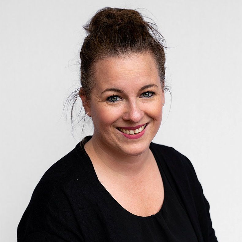 Vrouw met donkerblond haar en zwarte tuniek aan.