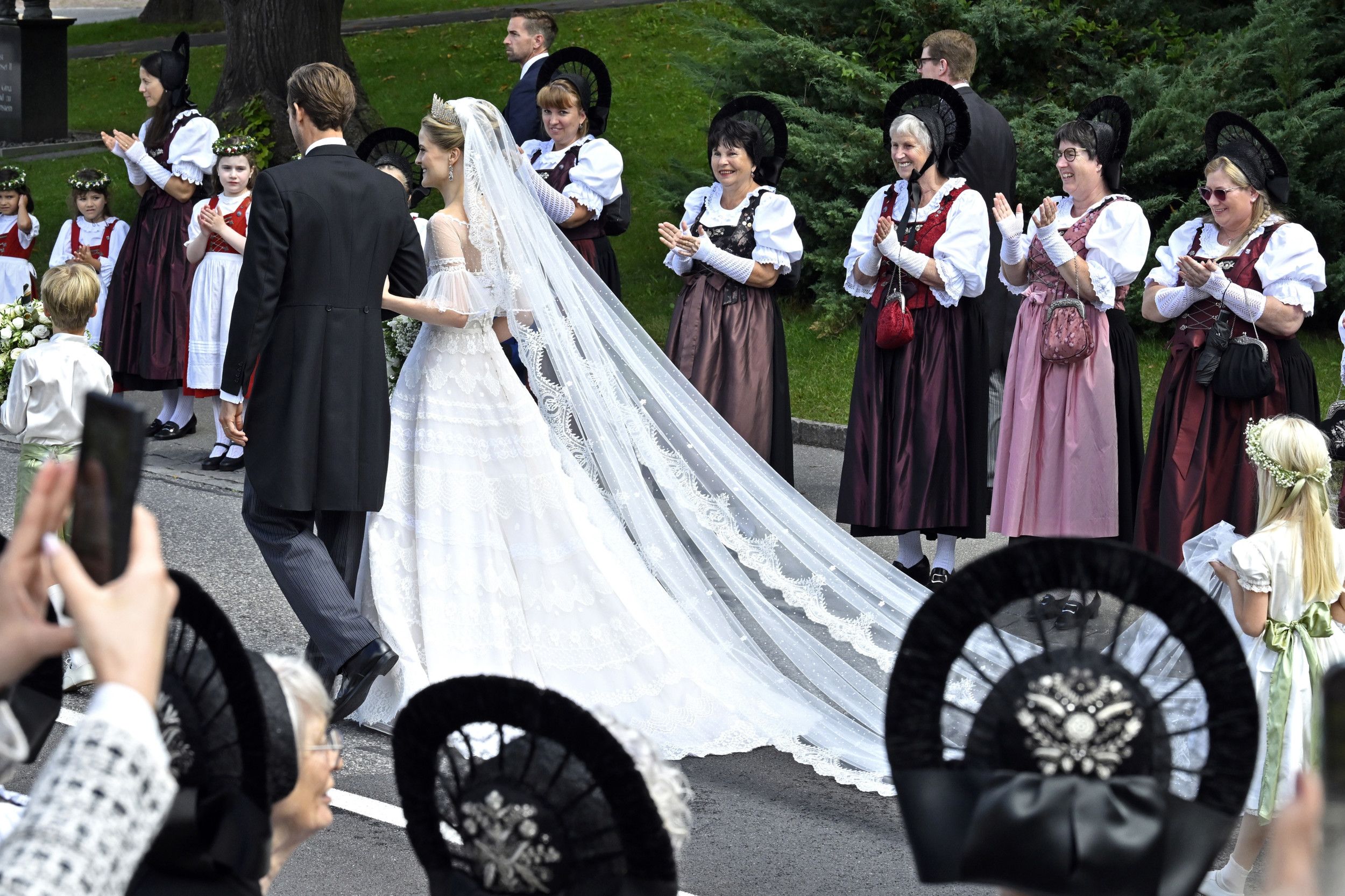 Bruidspaar loopt langs applaudisserende vrouwen in klederdracht
