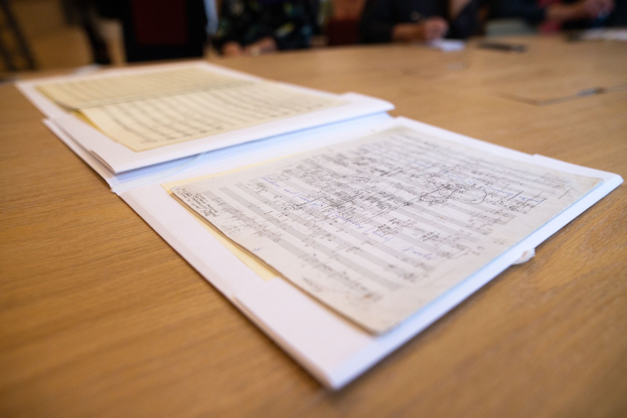 Manuscript van een muziekstuk, dat op een houten tafel ligt.