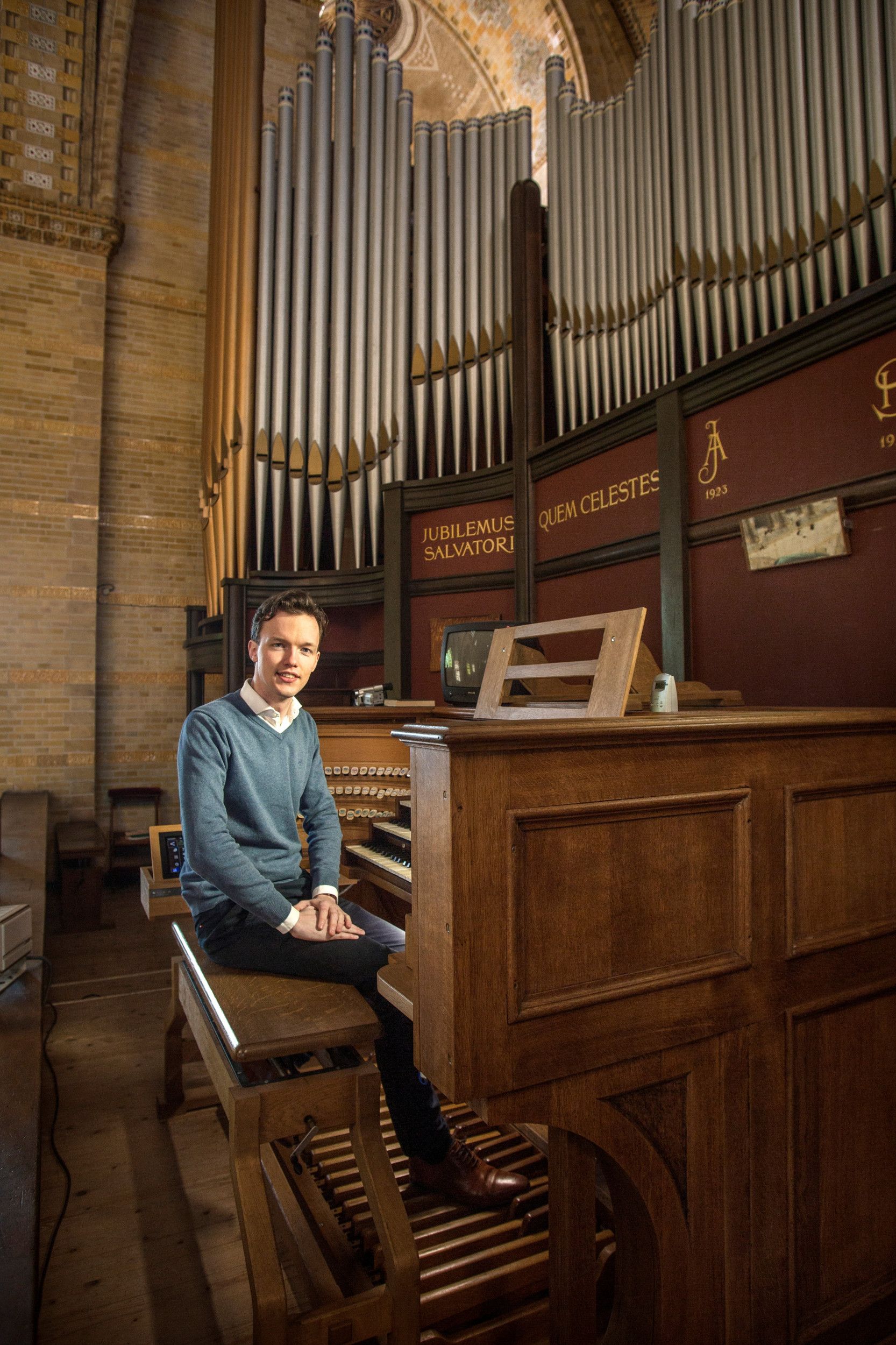 Een man zit op de orgelbank van een orgel in een grote kerk, dat vier klavieren en tientallen registers telt.