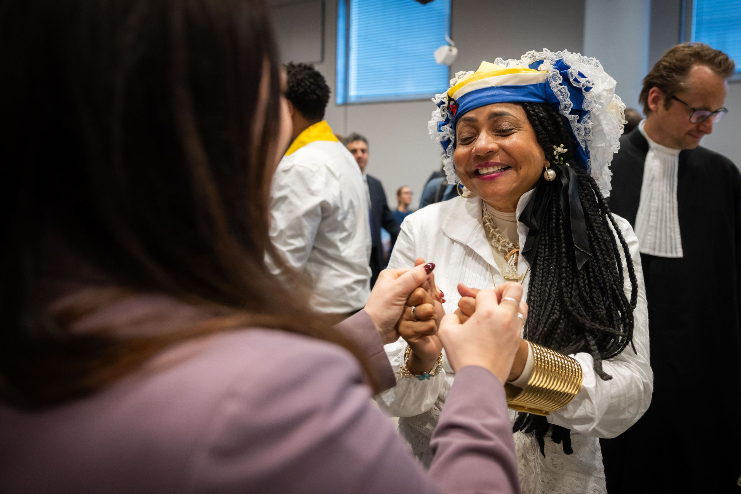 Een getinte vrouw met donker haar in traditionele kleding lacht hard.