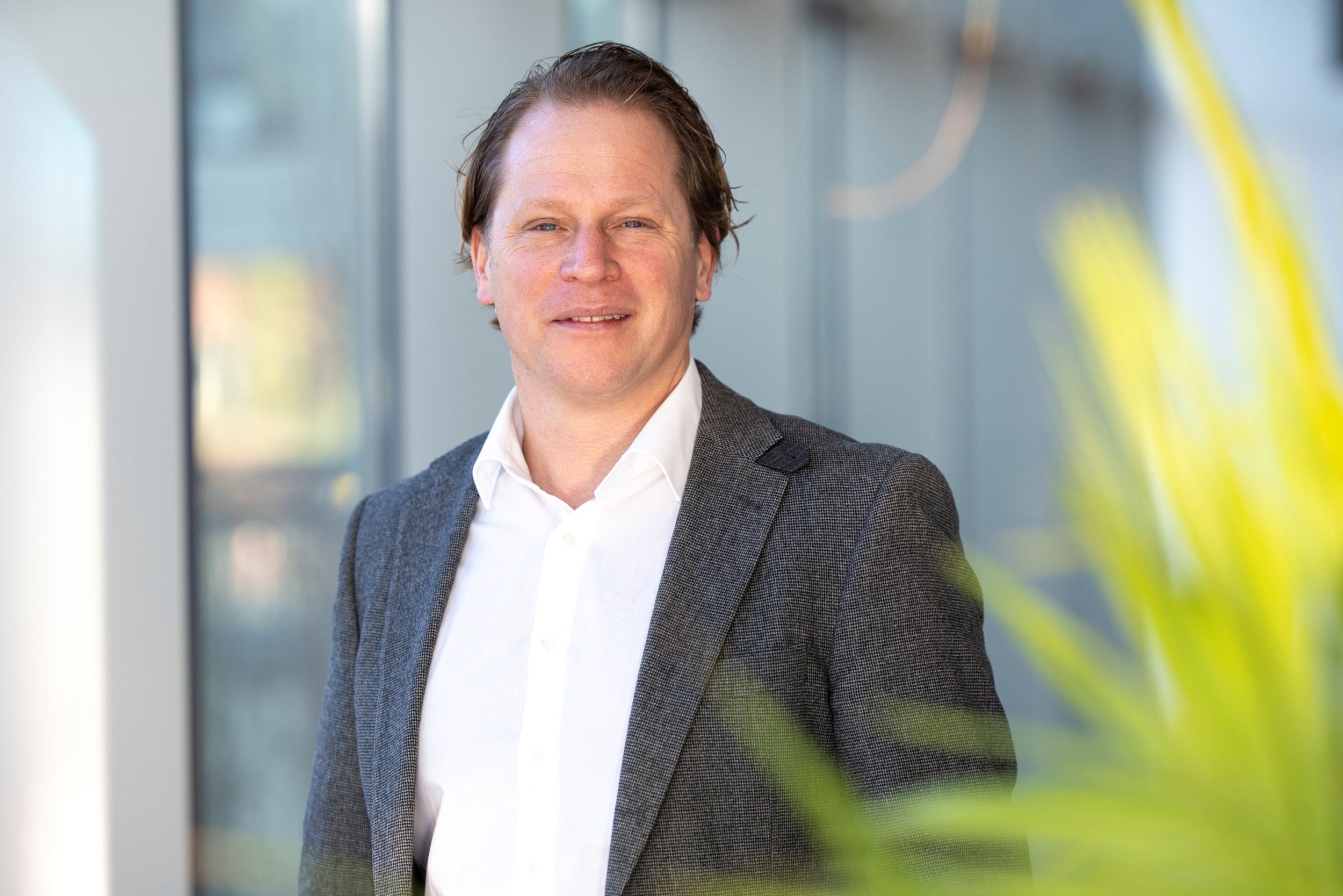 Een blanke man in een wit overhemd en een donker colbertje.