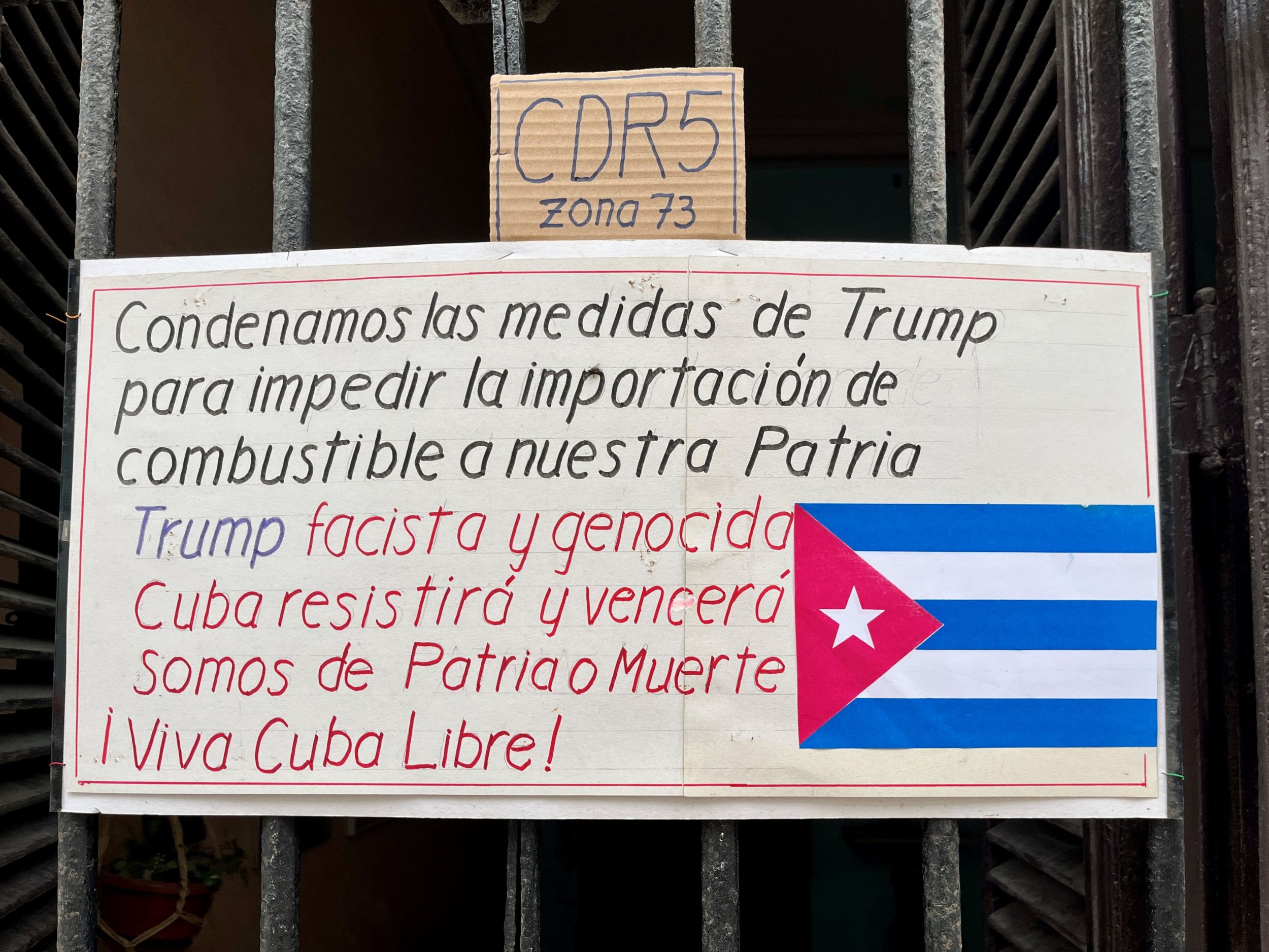 Een wit bord met daarop de Cubaanse vlag en enkele regels tekst. 