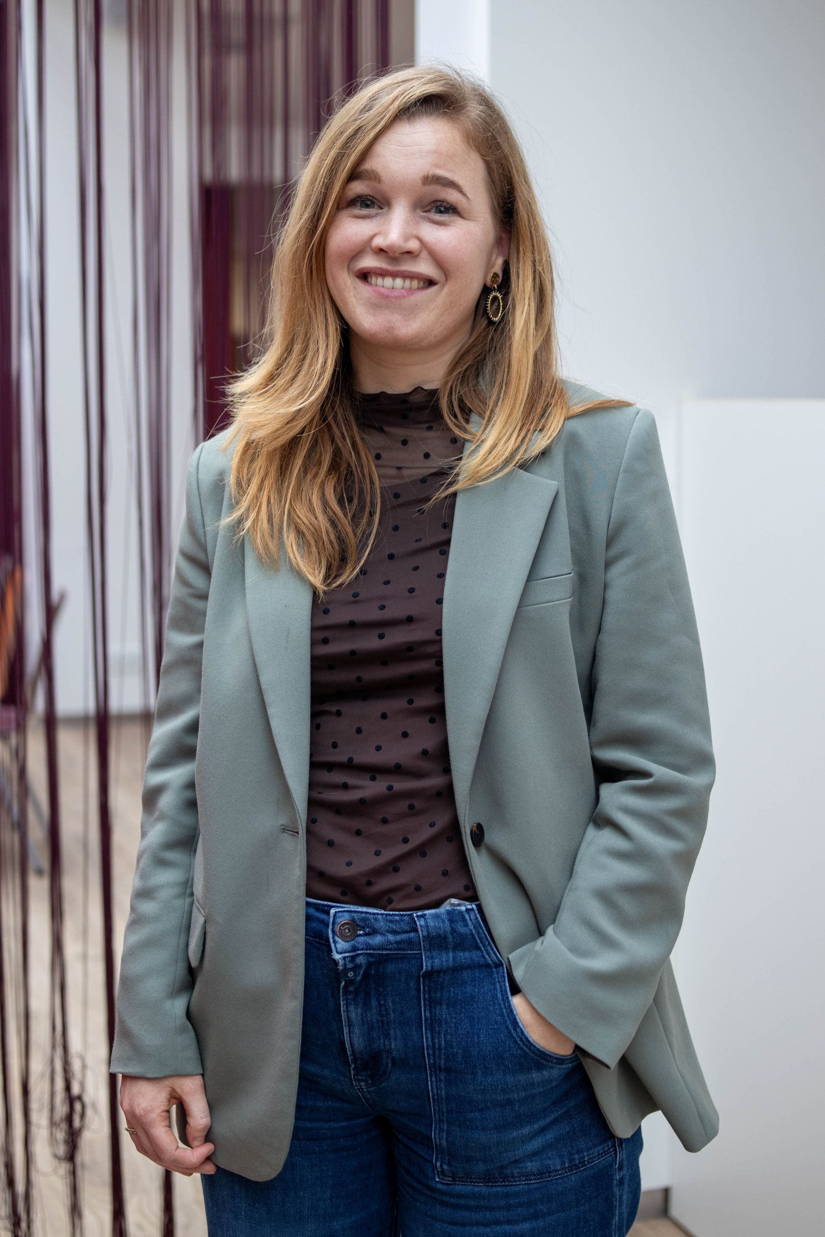 Een vrouw met blond haar in een lichtblauw colbert.