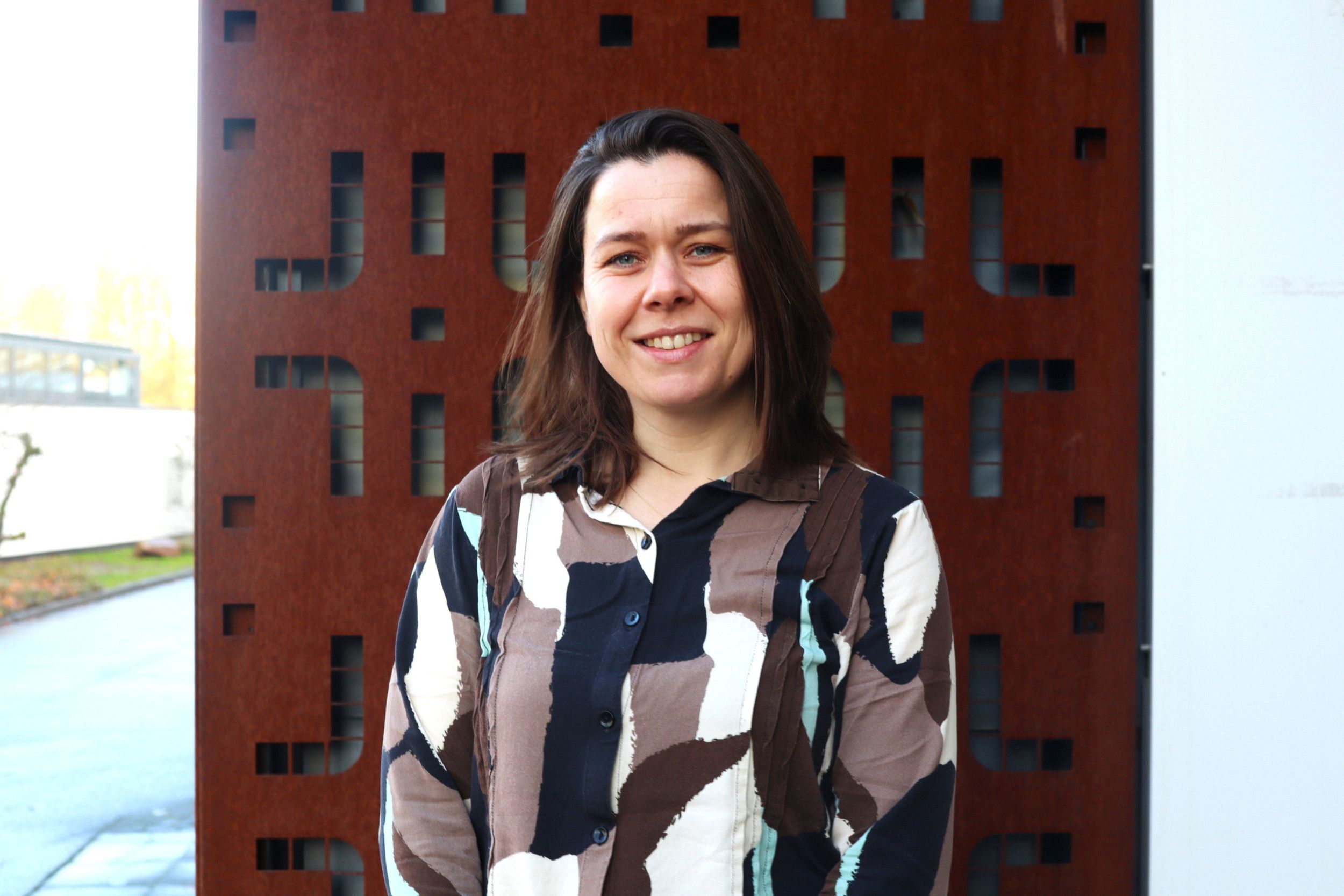 Een vrouw met kort bruin haar in een blouse met een bruin motief.