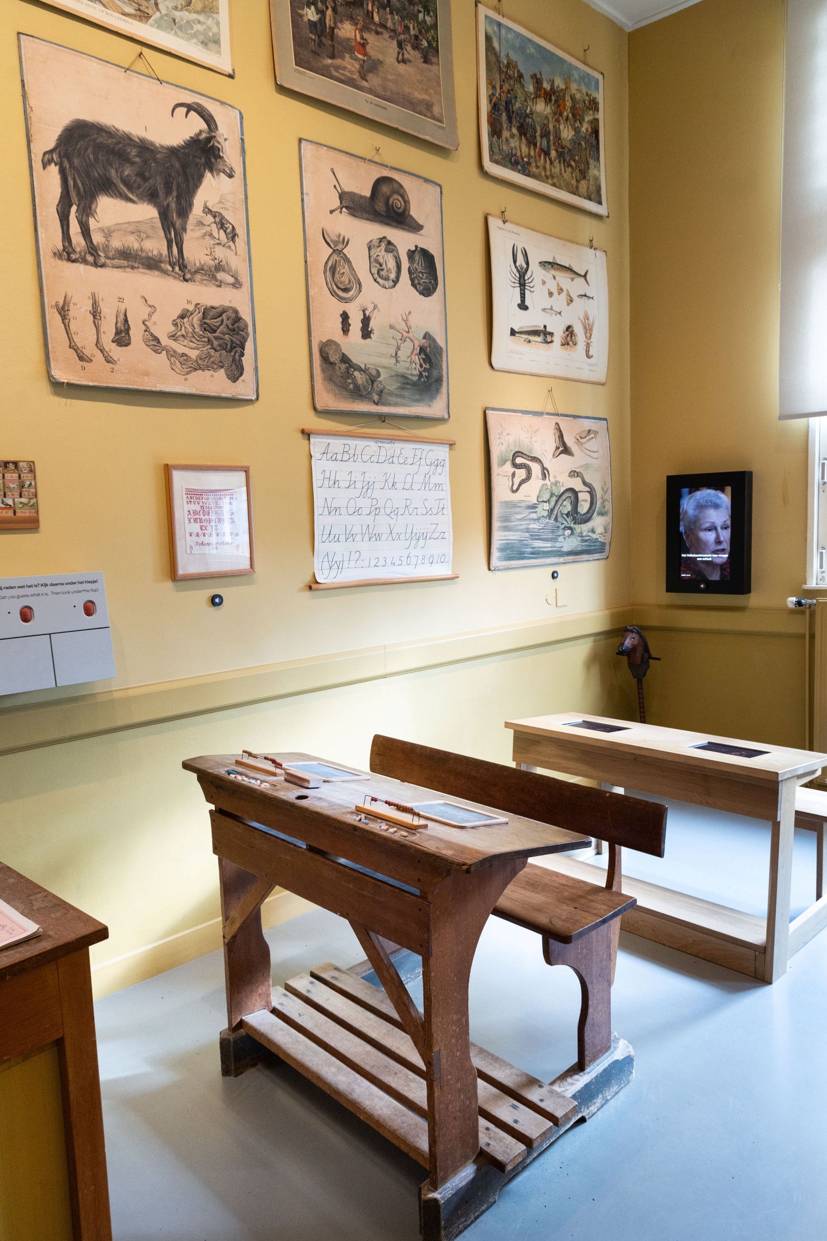 Links liggen wat gekleurde krijtjes, rechts staat een telraam met rode ballen.