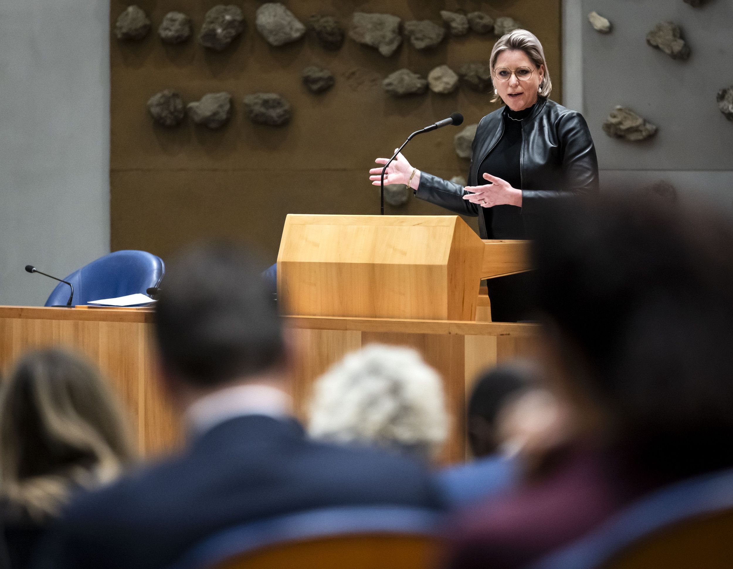 Vrouw spreekt Kamerleden toe vanachter spreekgestoelte.