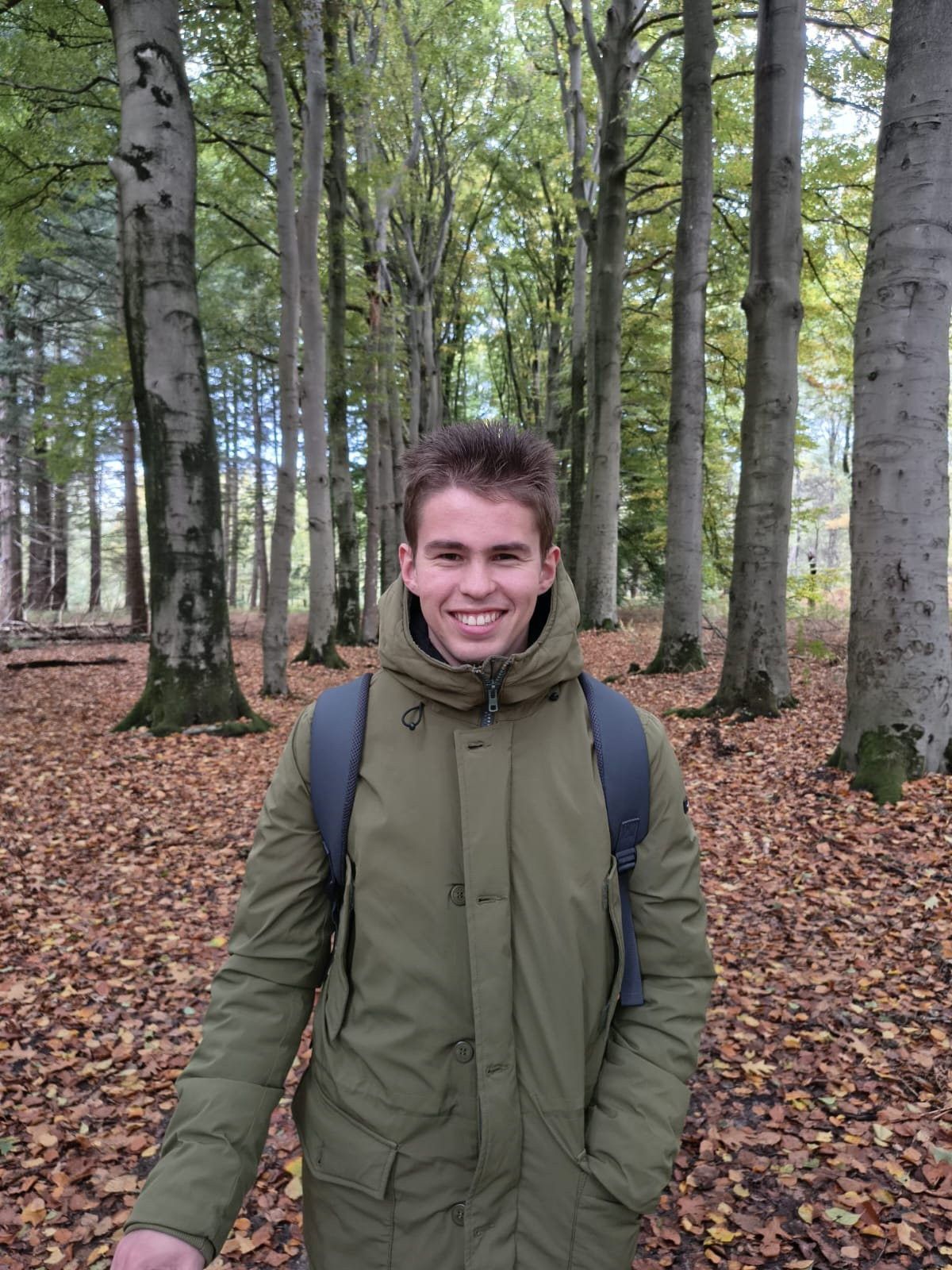 Jongeman met groene jas in bos