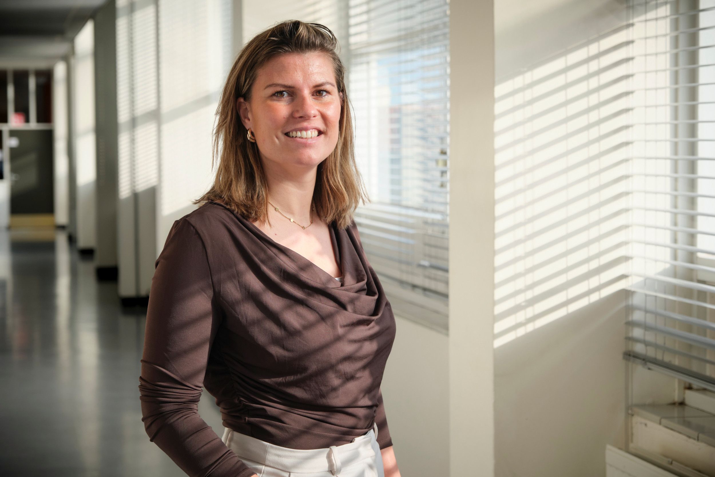 Portretfoto van een vrouw met halflang bruin haar en een bruine blouse.