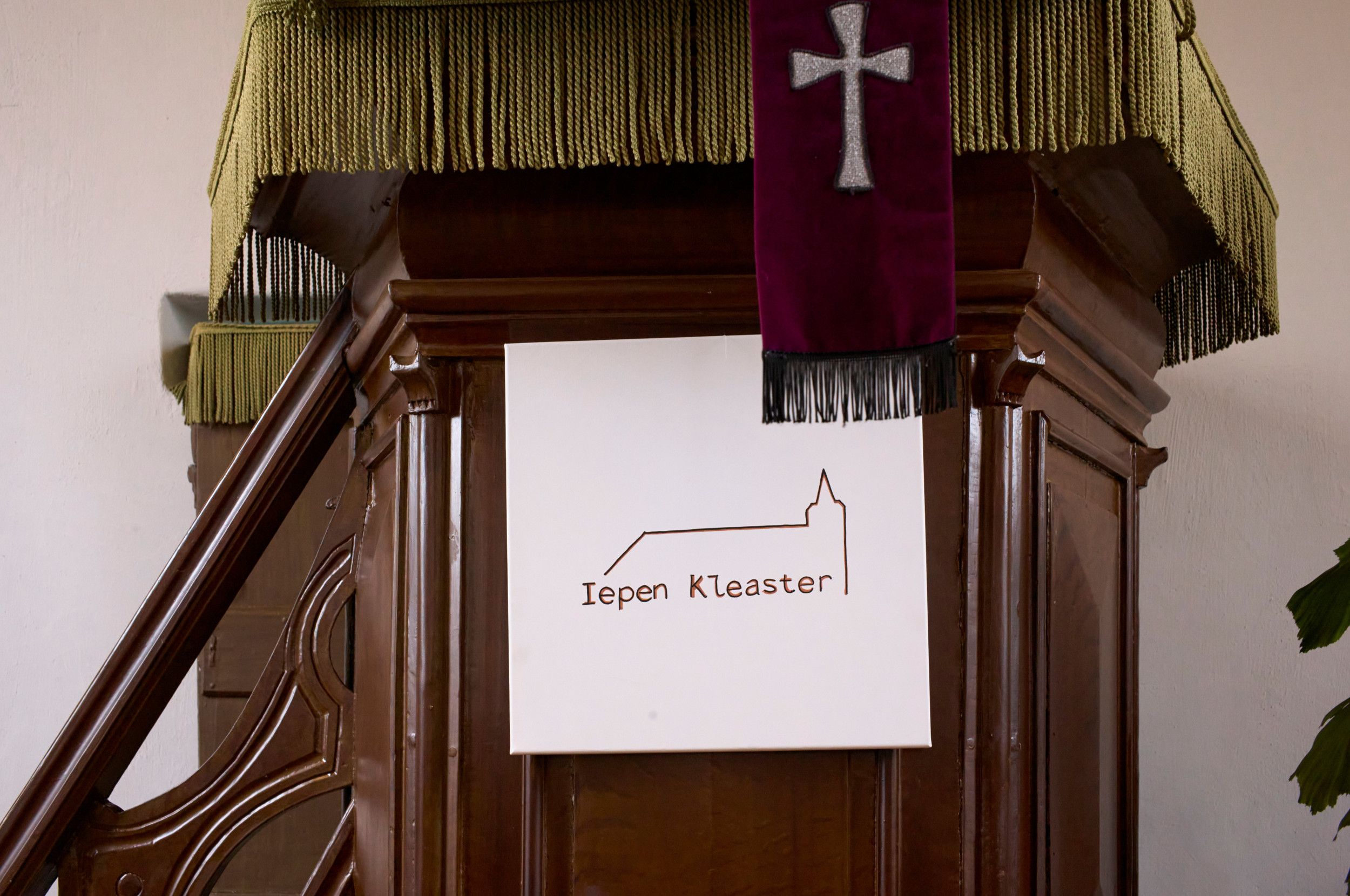 Aan de houten preekstoel hangt een bordje met de tekst Iepen Kleaster.