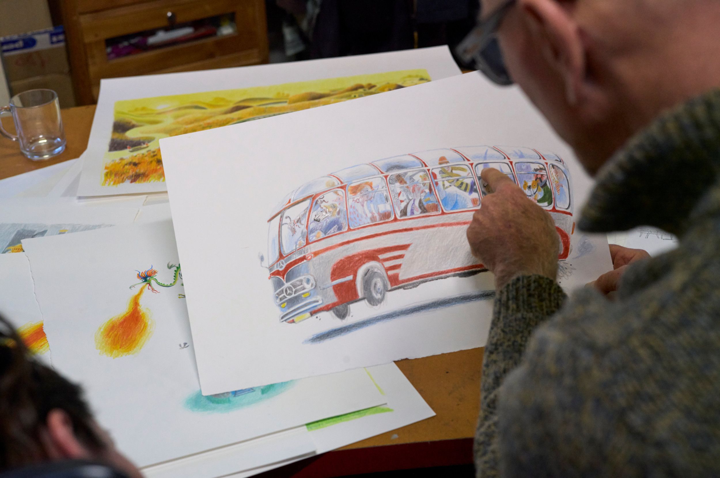 Man op de voorgrond wijst iets aan op een tekening van een rood-wit Volkswagenbusje.