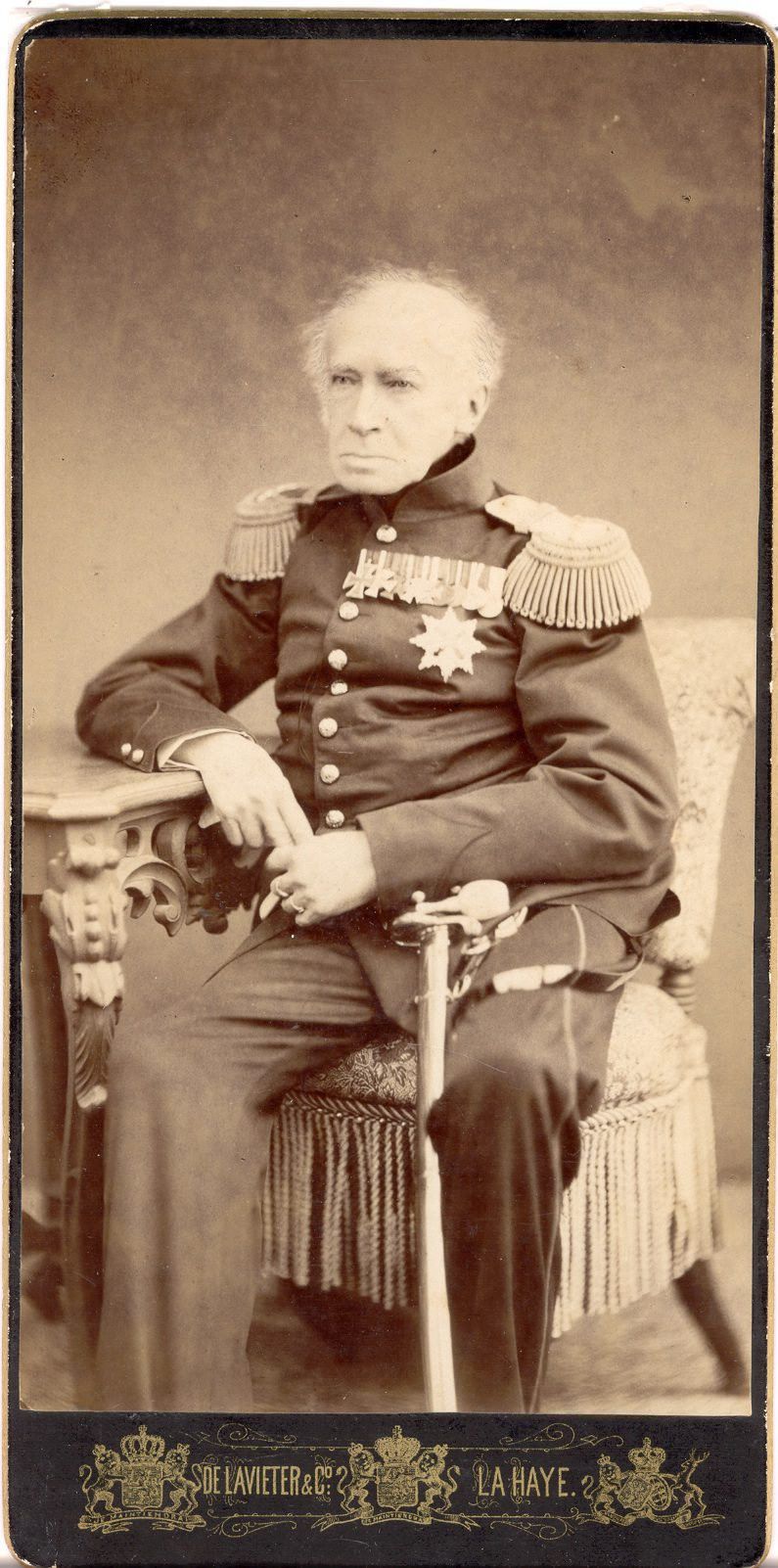 Een oudere man met een zorgelijk gezicht. Zijn sabel staat naast zijn been.