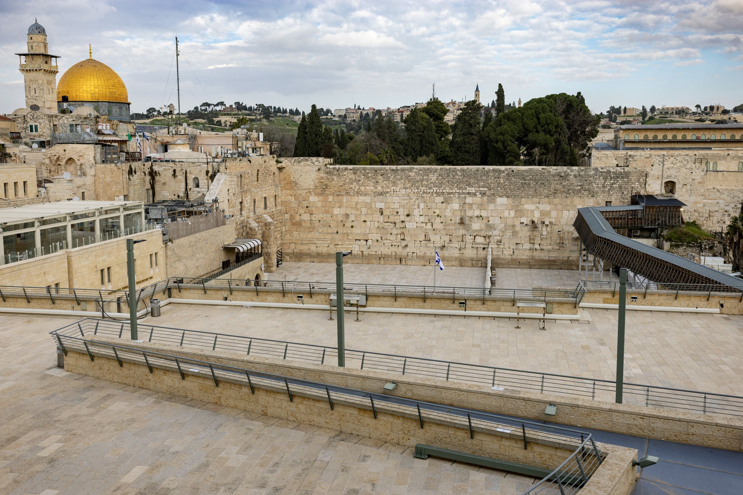 Overzichtsfoto van het oude Jeruzalem. In het midden een hoge muur. Links op de achtergrond een toren en een gouden koepel