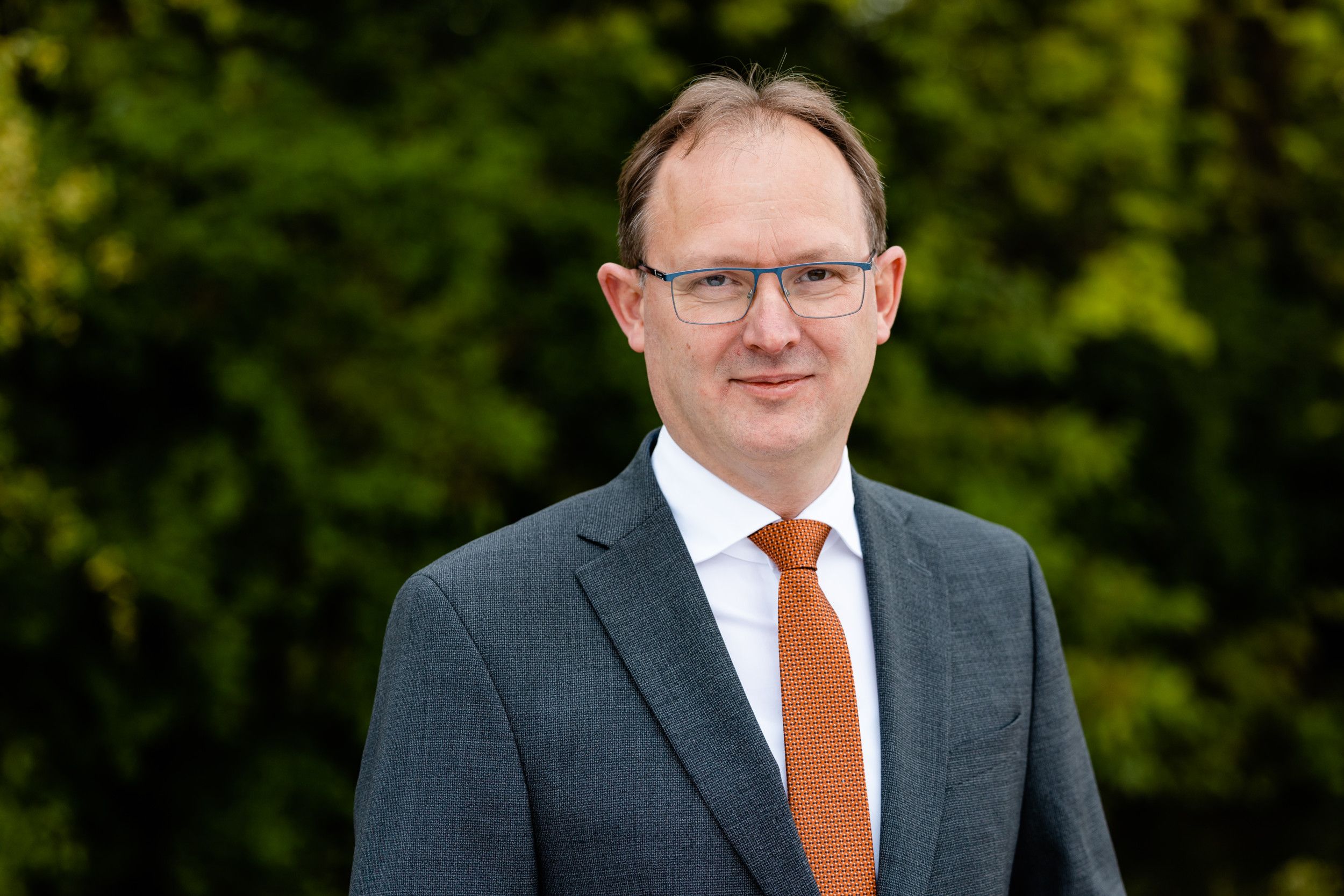 Man in grijs pak met oranje das.