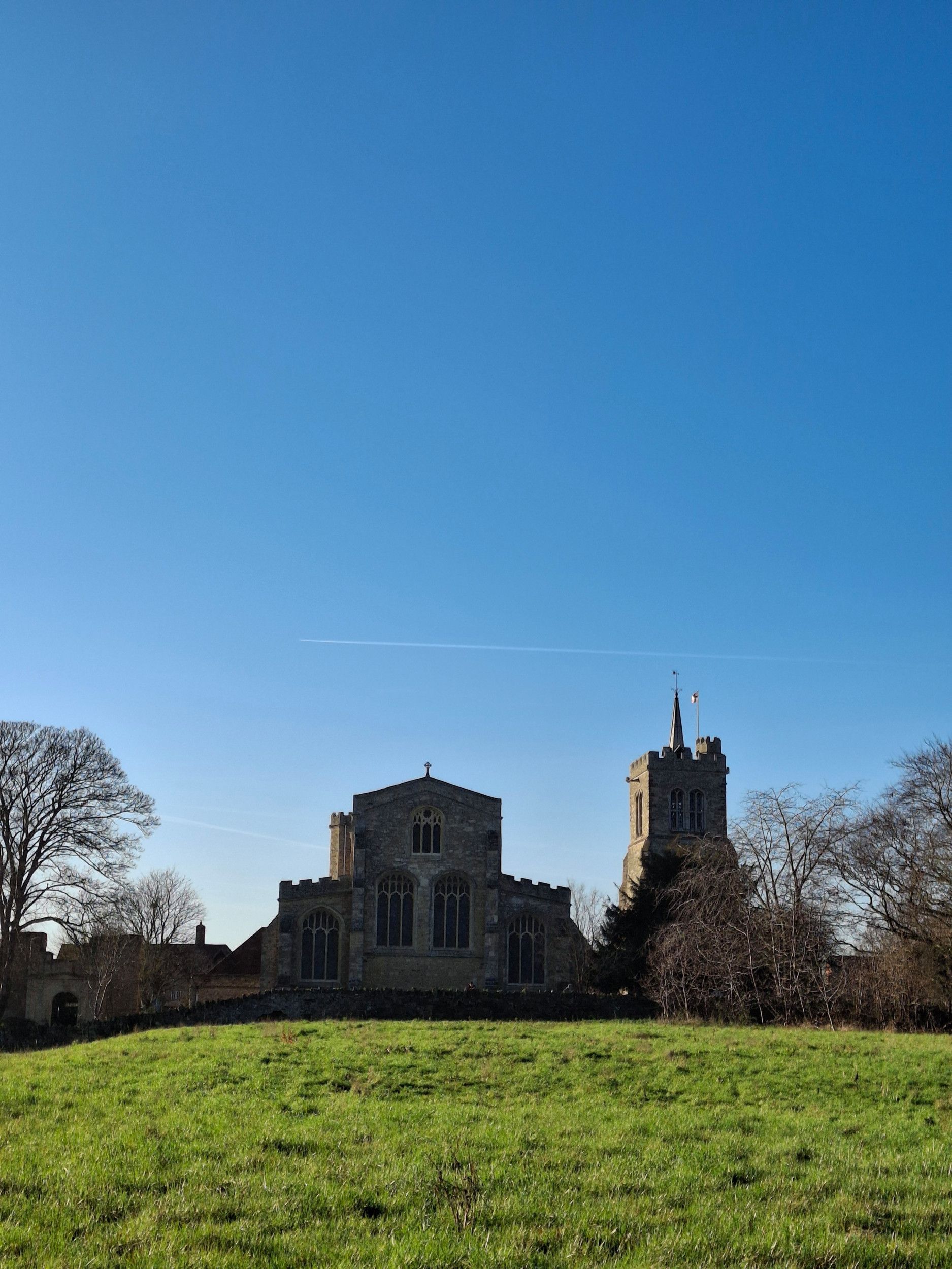 Een oud kerkgebouw, waarvan de contouren afsteken tegen de helderblauwe lucht.
